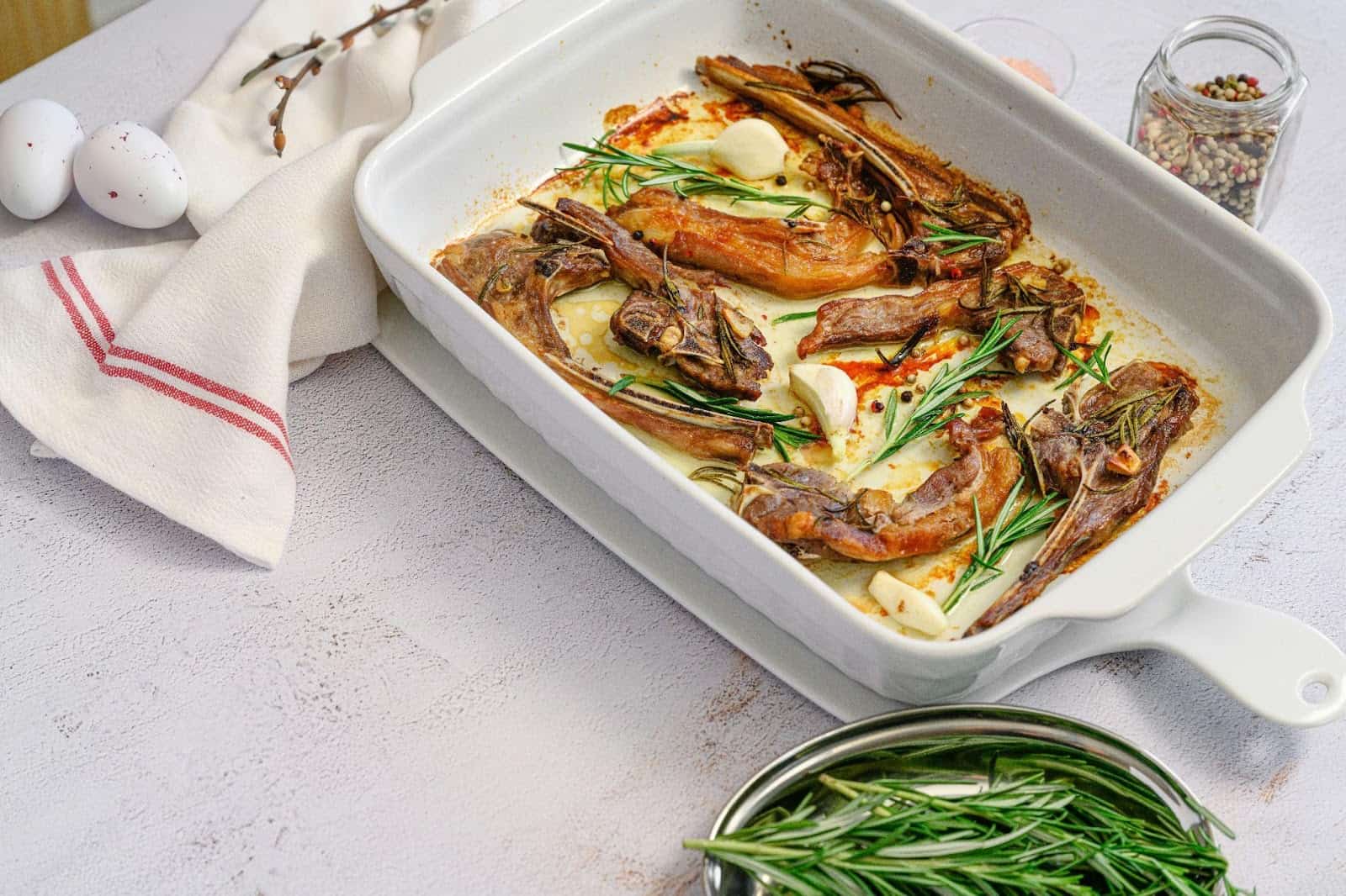 Lambchops set in a rectangular white dish with fresh herbs as a garnish