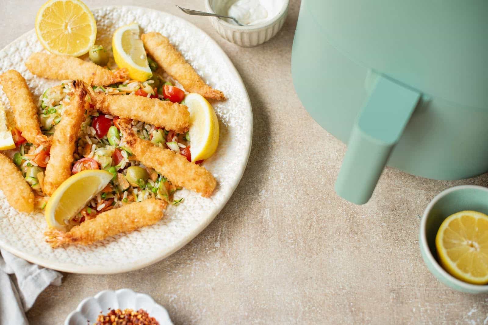 Zucchini fritters set on a plate with slices of lemon and a fried rice mixture