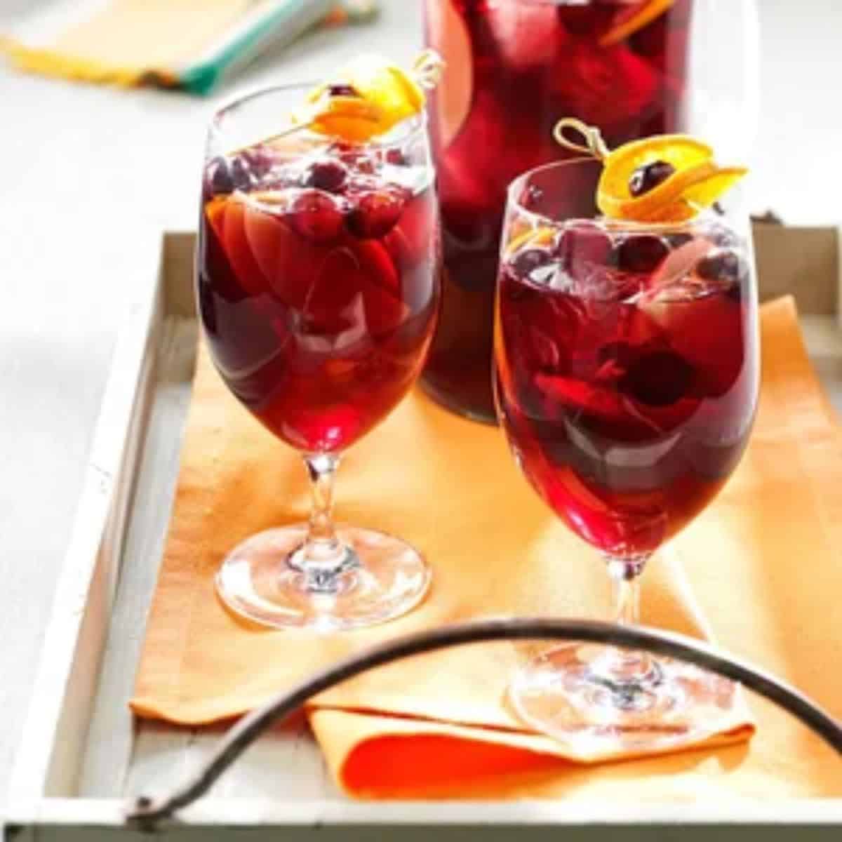 Two delicious Cranberry orange sangria's in wine glasses placed on a tray.