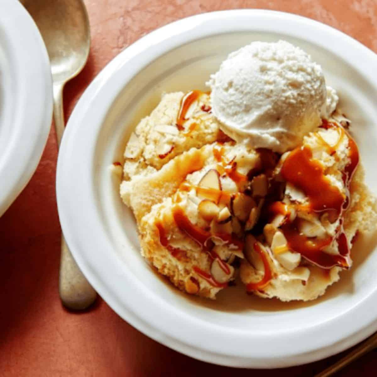 A slice of Instant Pot Magic Apple Cake, featuring a moist, fluffy texture, topped with a dollop of ice cream on the side and a caramel sauce on top.