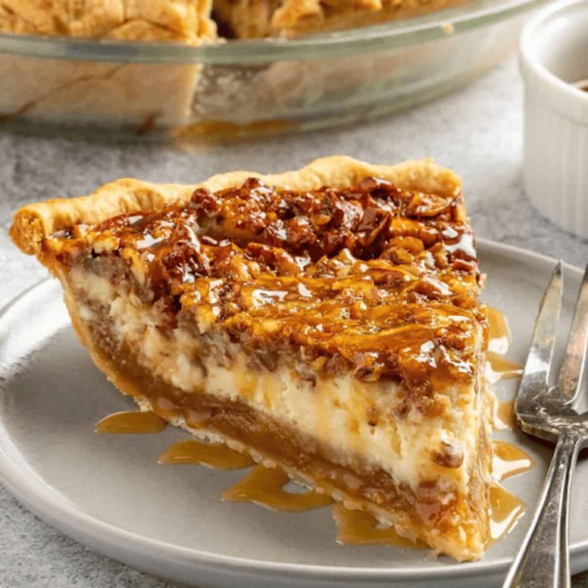 A slice of pecan cheesecake pie, featuring a creamy cheesecake layer topped with crunchy caramelized pecans, all nestled in a flaky crust, served on a plate with a drizzle of caramel sauce.