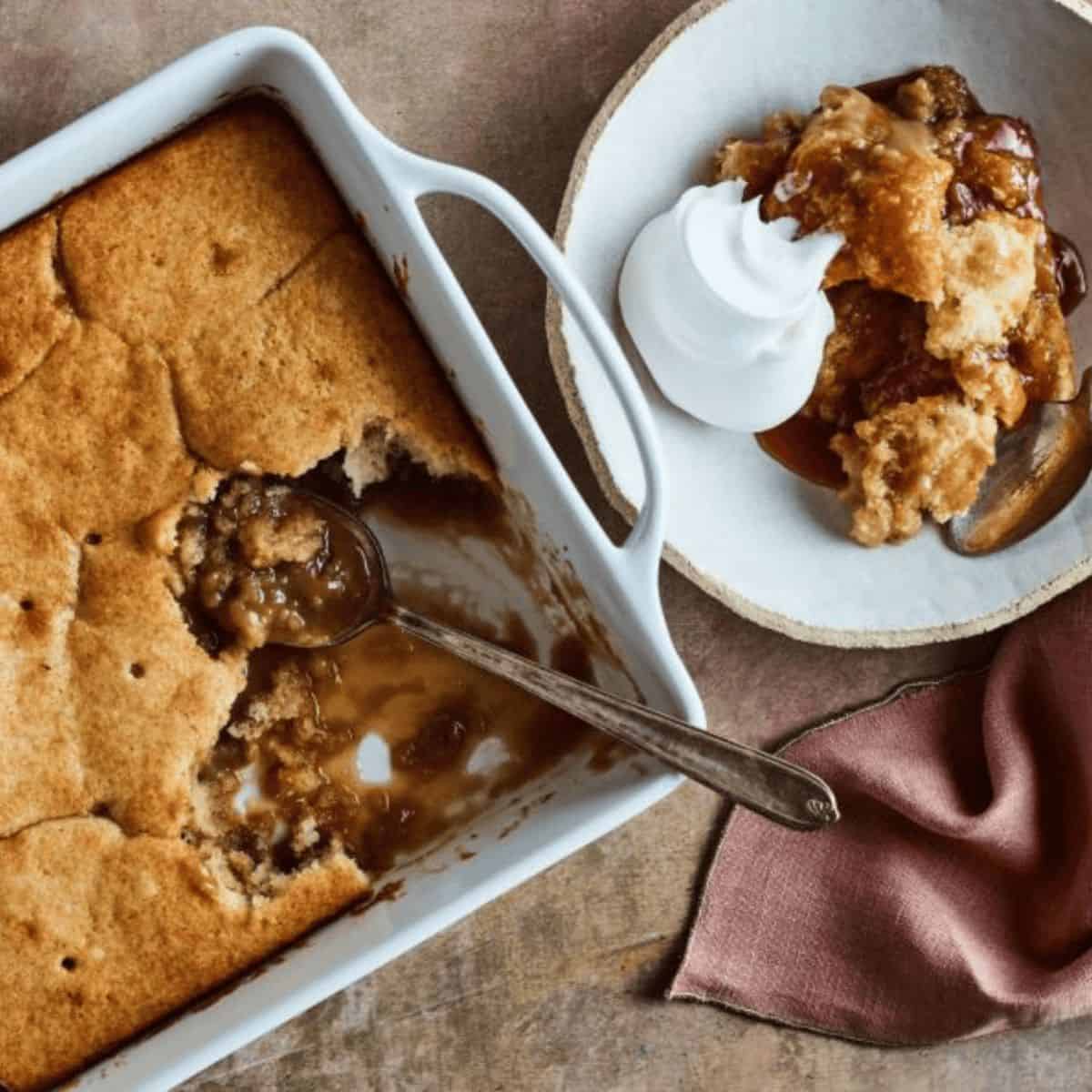 A warm serving of Pouding Chômeur, featuring a rich cake soaked in sweet caramel sauce, and served in a white bowl, evoking a comforting and indulgent dessert.