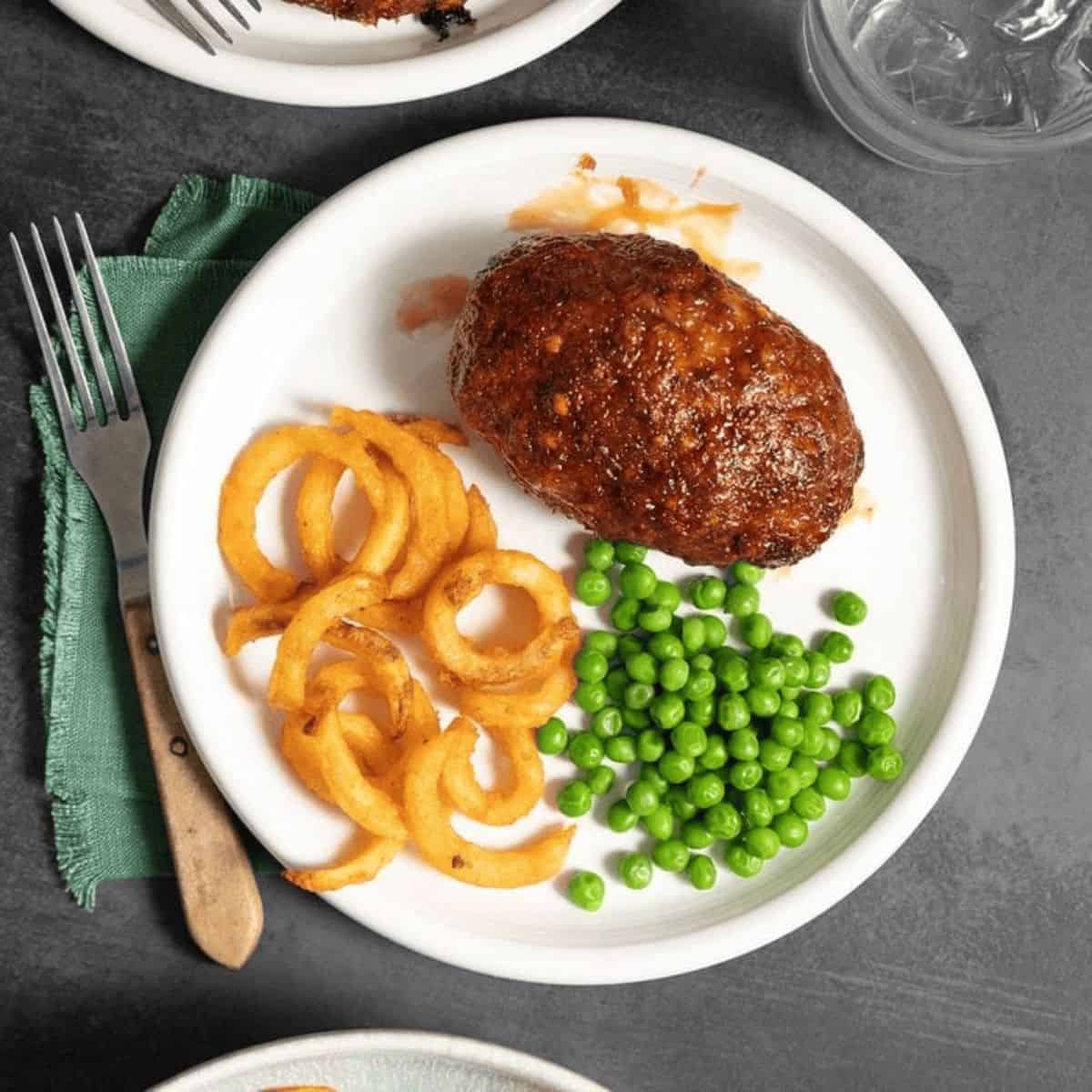 An appetizing meal featuring air-fryer meatloaf, and fried onions and peas on the side.