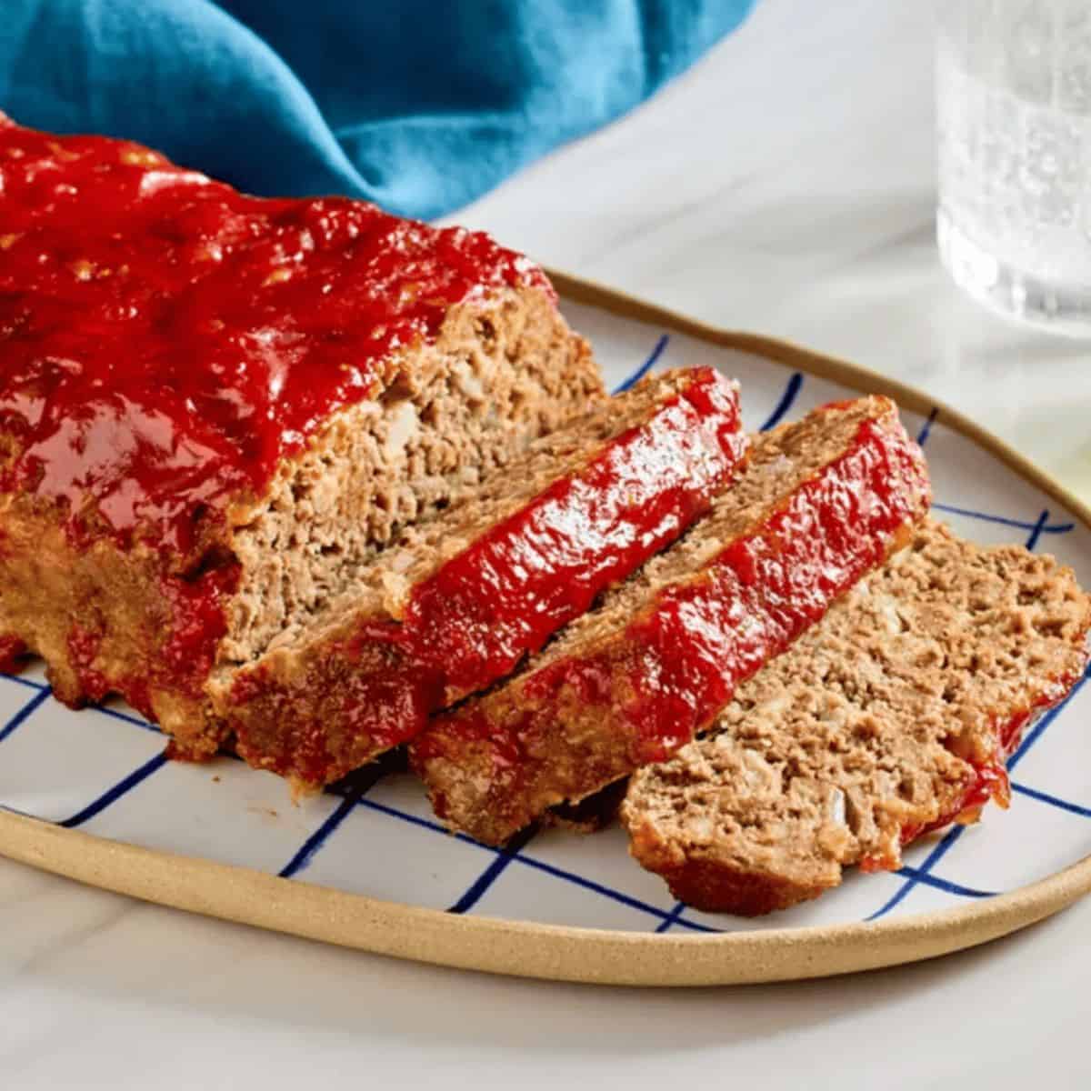Brown sugar meatloaf cut into slices on an oval plate.
