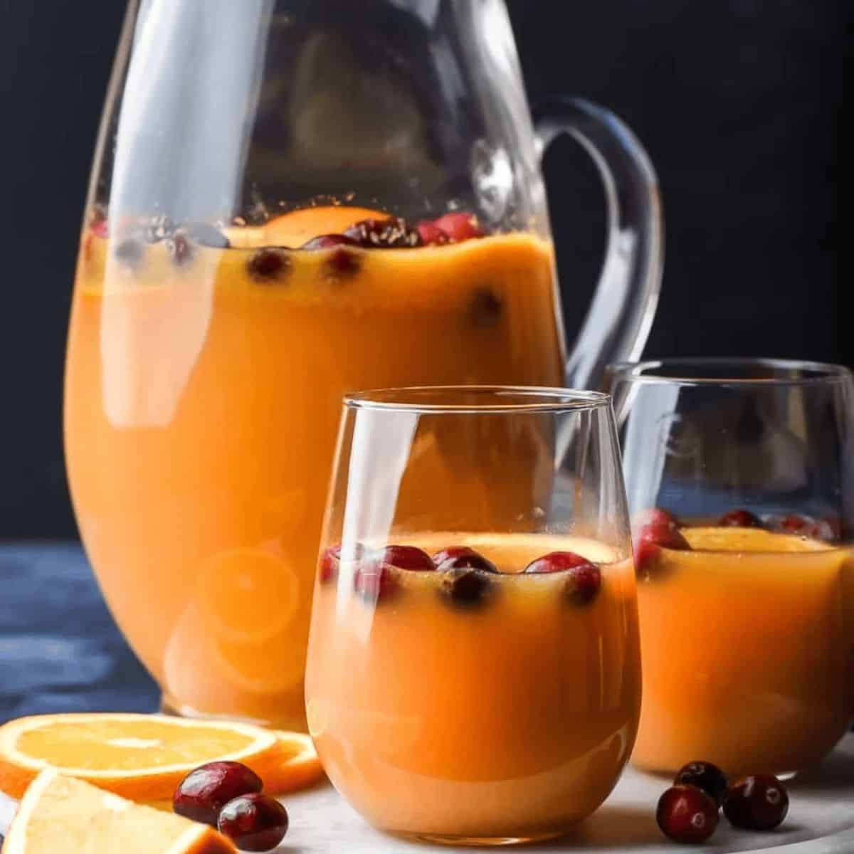 A freshening drink featuring Christmas morning punch in a jug and two glasses, with fresh cranberries on top.