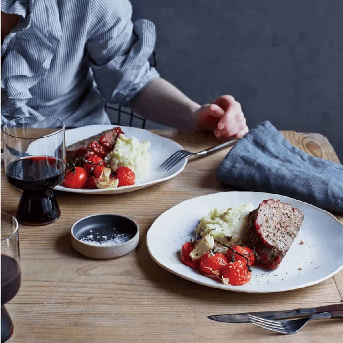 Gluten-free beef, turkey and mushroom meatloaf, alongside cooked tomatoes and mashed potatoes.