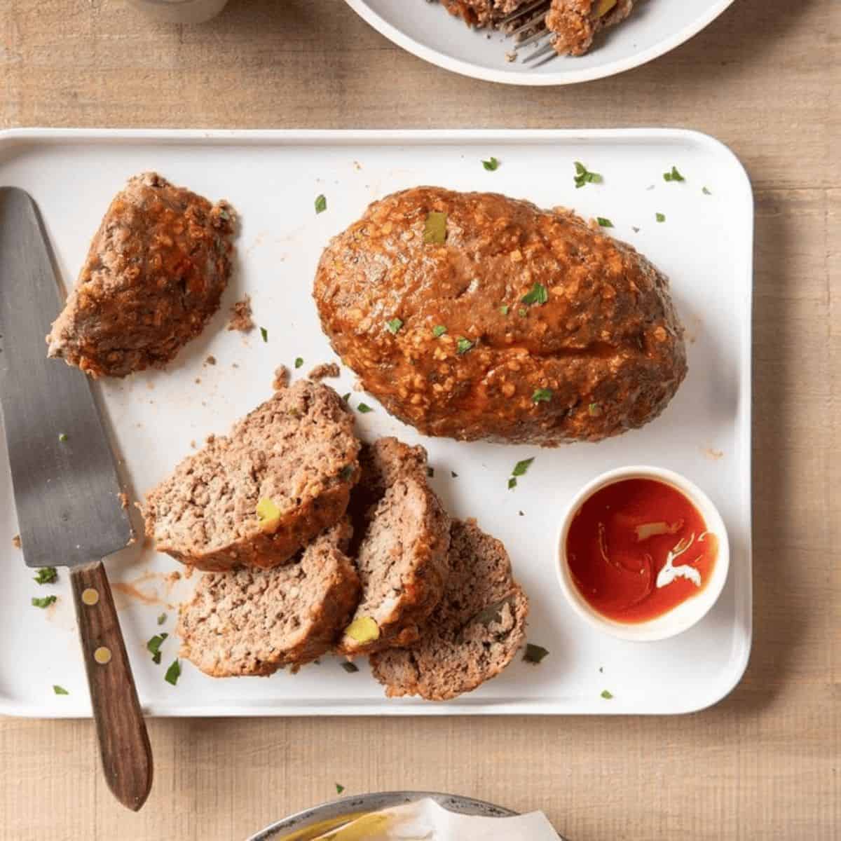 An appetizing meal featuring grilled meatloaf and a dipping sauce.