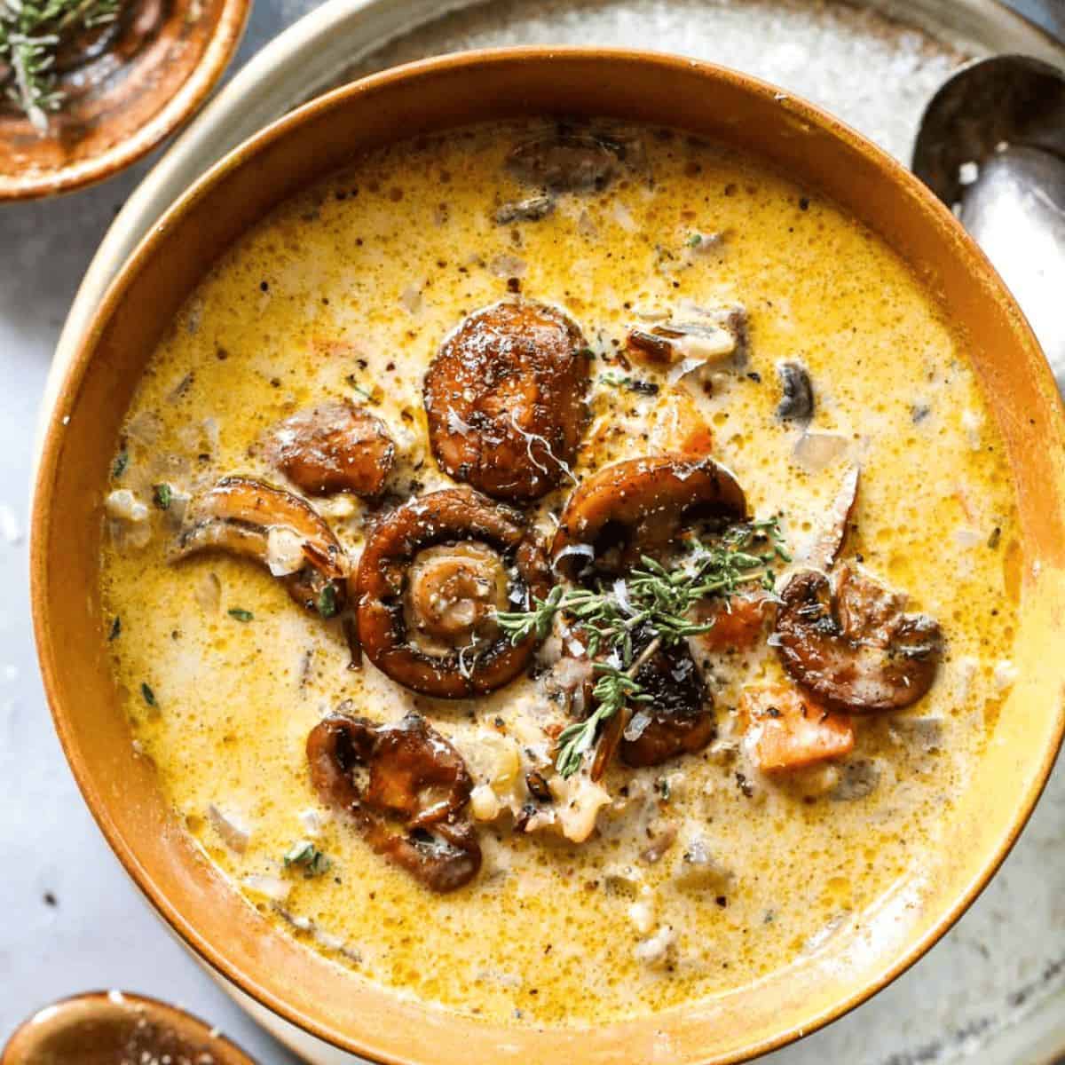 A yummy treat with wild rice and mushroom soup in a brown dish with whole mushrooms on top.