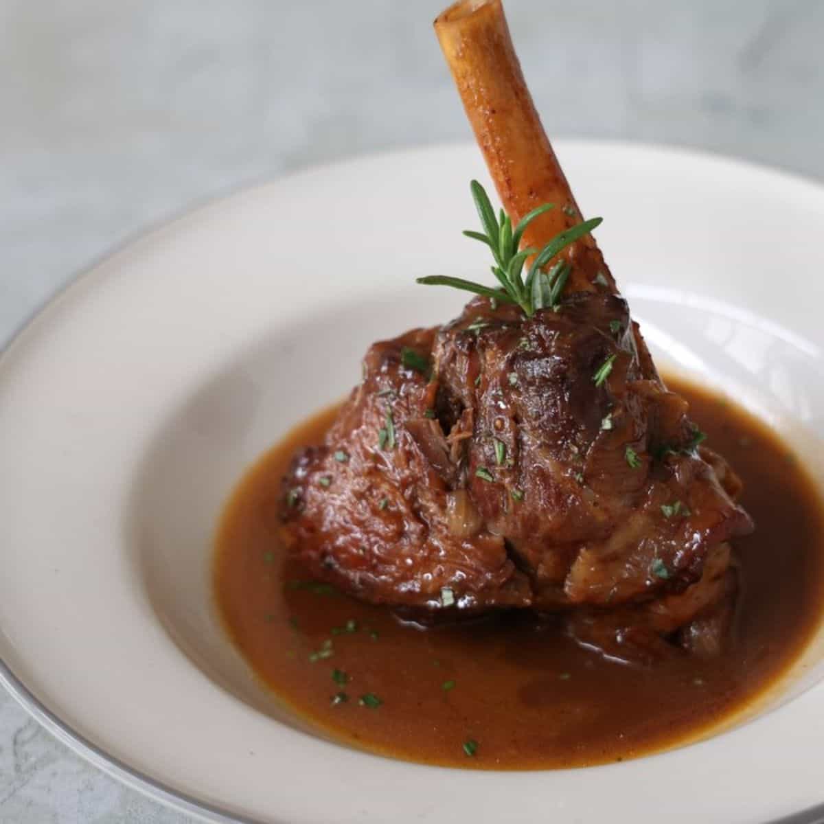A yummy meal with braised lamb shanks in a white plate. 