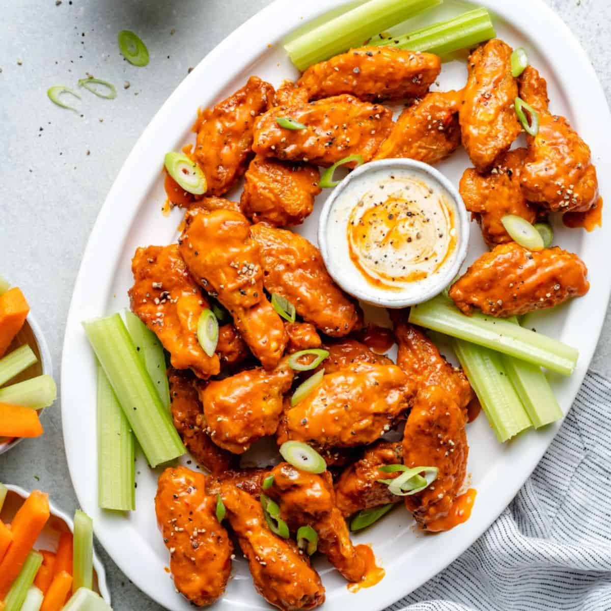 A yummy meal with buffalo chicken wings in a dish with a creamy dip. 