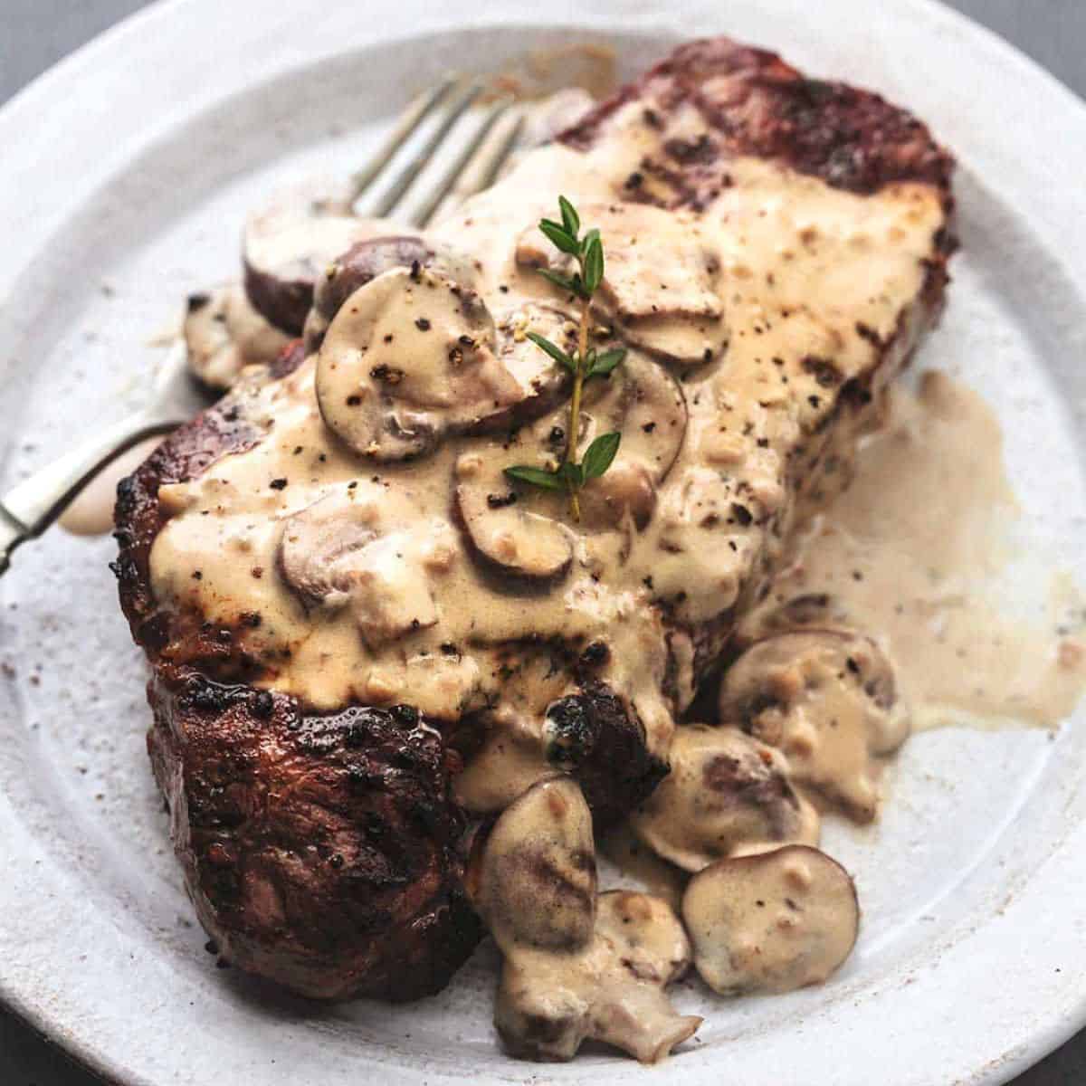 Creamy mushroom steak with a silver fork served in a plate. 