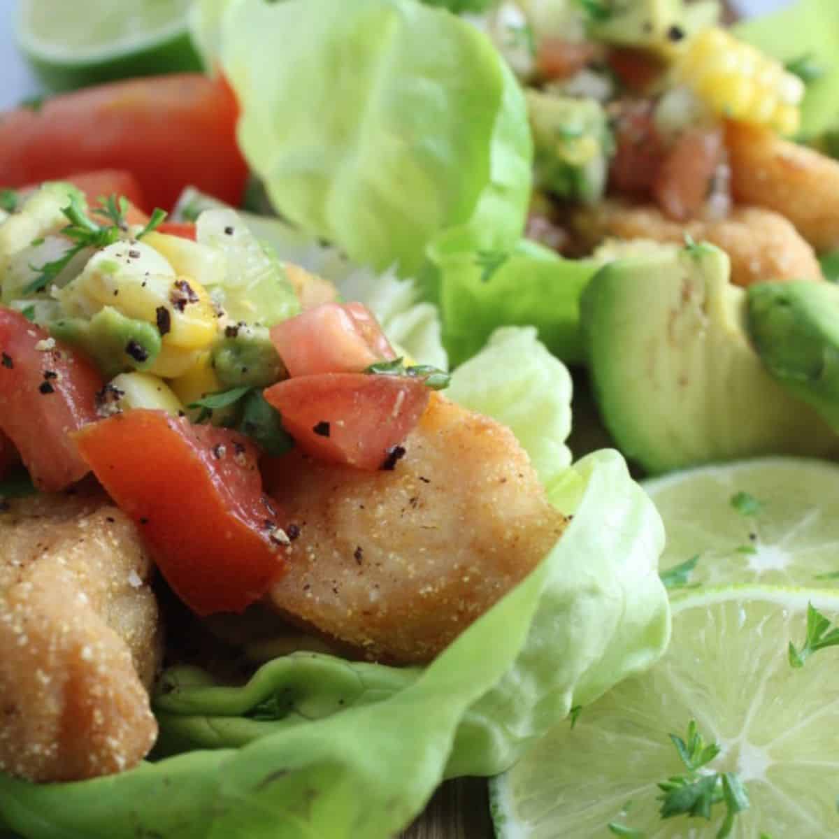 A flavorful meal with crispy fish tacos served with sliced lemons. 