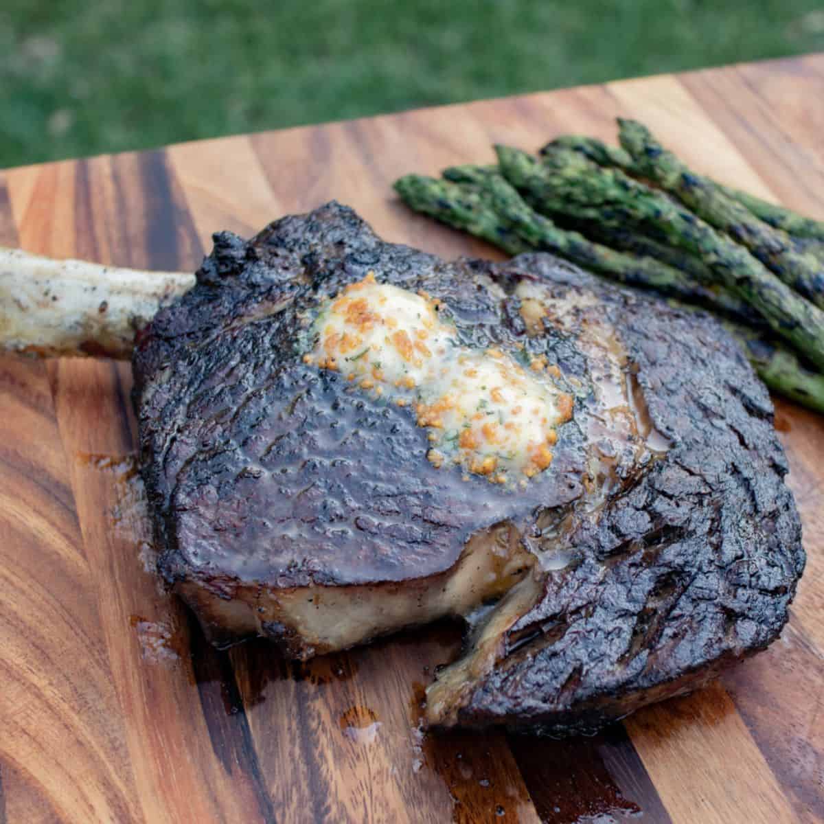 A flavorful meal with a grilled ribeye steak with garlic butter on a wooden tray. 