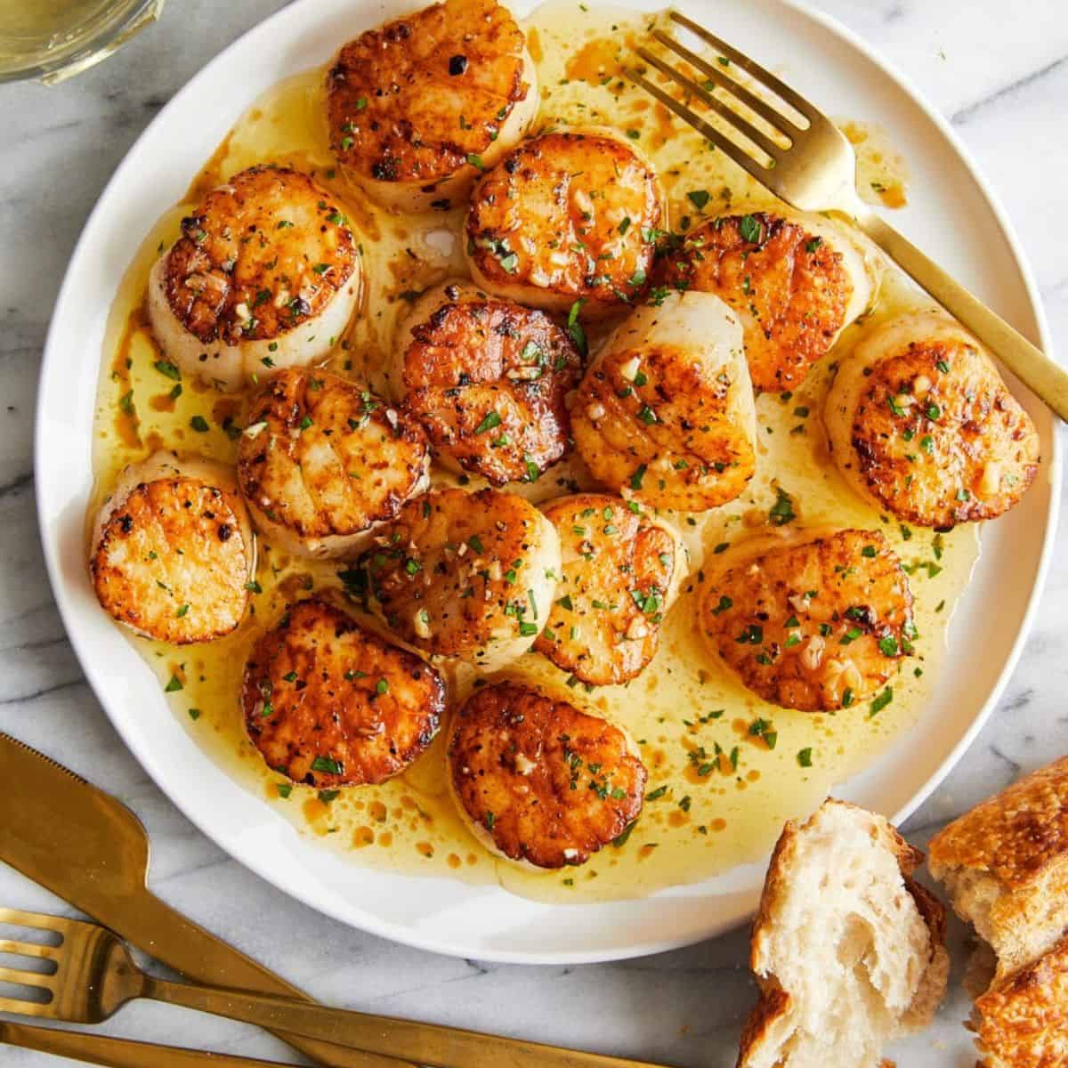 A yummy meal with lemon butter scallops in a plate with a fork. 