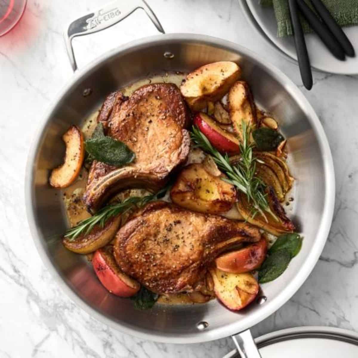 A yummy meal with pork chops with apple and sage in a pan. 