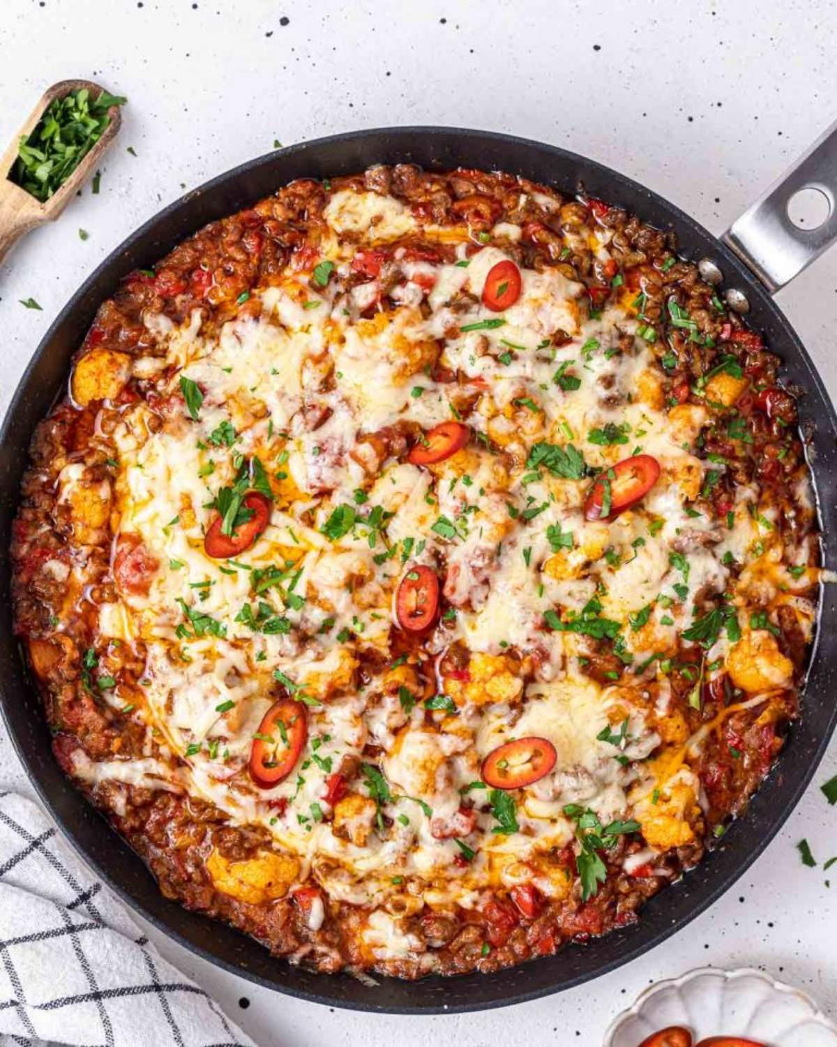 Easy ground beef and cauliflower stovetop casserole with melted cheese and chili peppers in a skillet for a quick dinner recipe