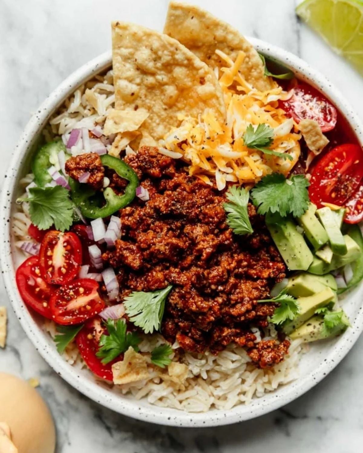 Ground beef taco bowl served with rice, tomatoes, avocado, cheese, and tortilla chips for an easy dinner