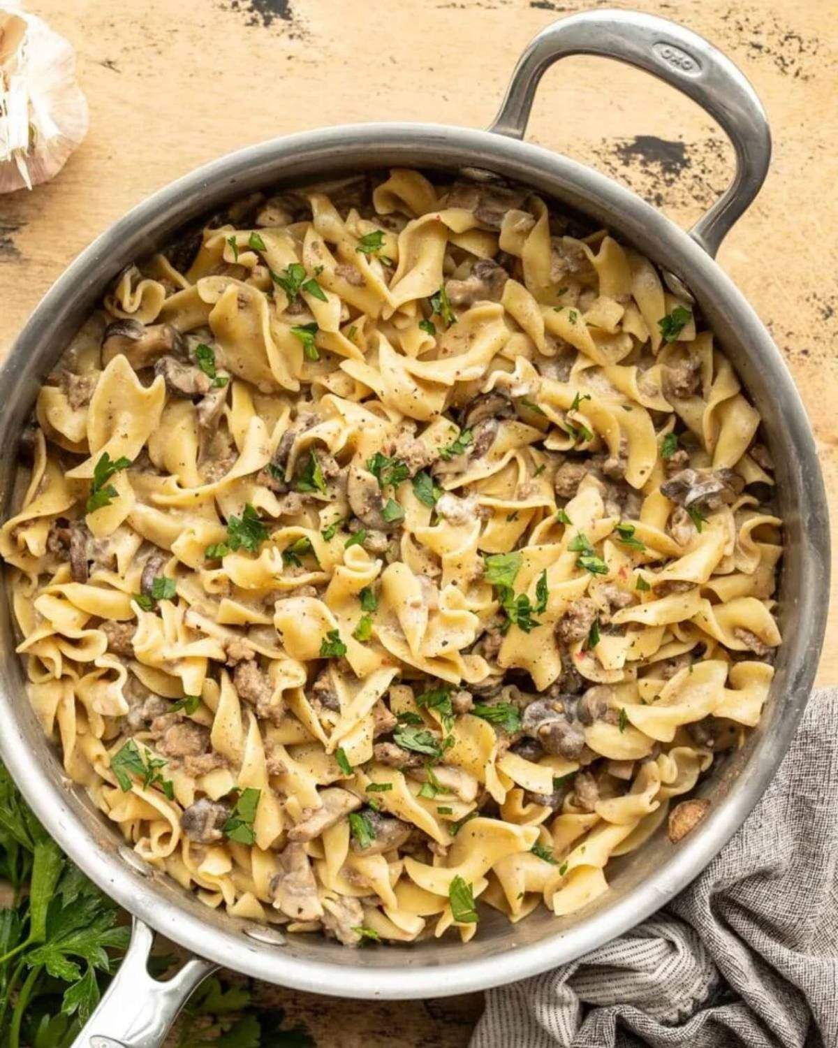 Ground beef and mushroom stroganoff with egg noodles in a skillet, making an easy dinner recipe