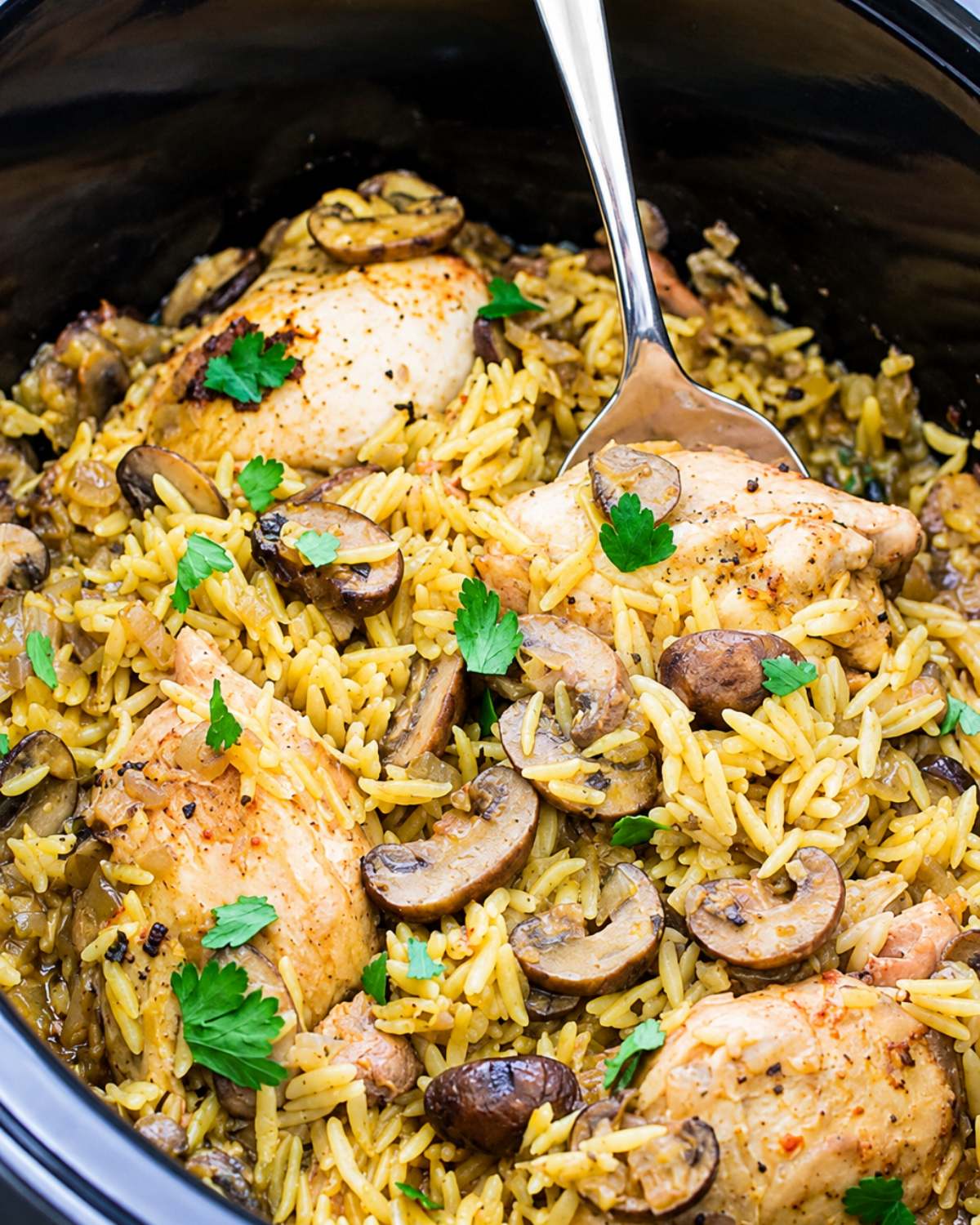 Crockpot Chicken and Mushrooms with orzo pasta inside a slow cooker garnished with fresh parsley