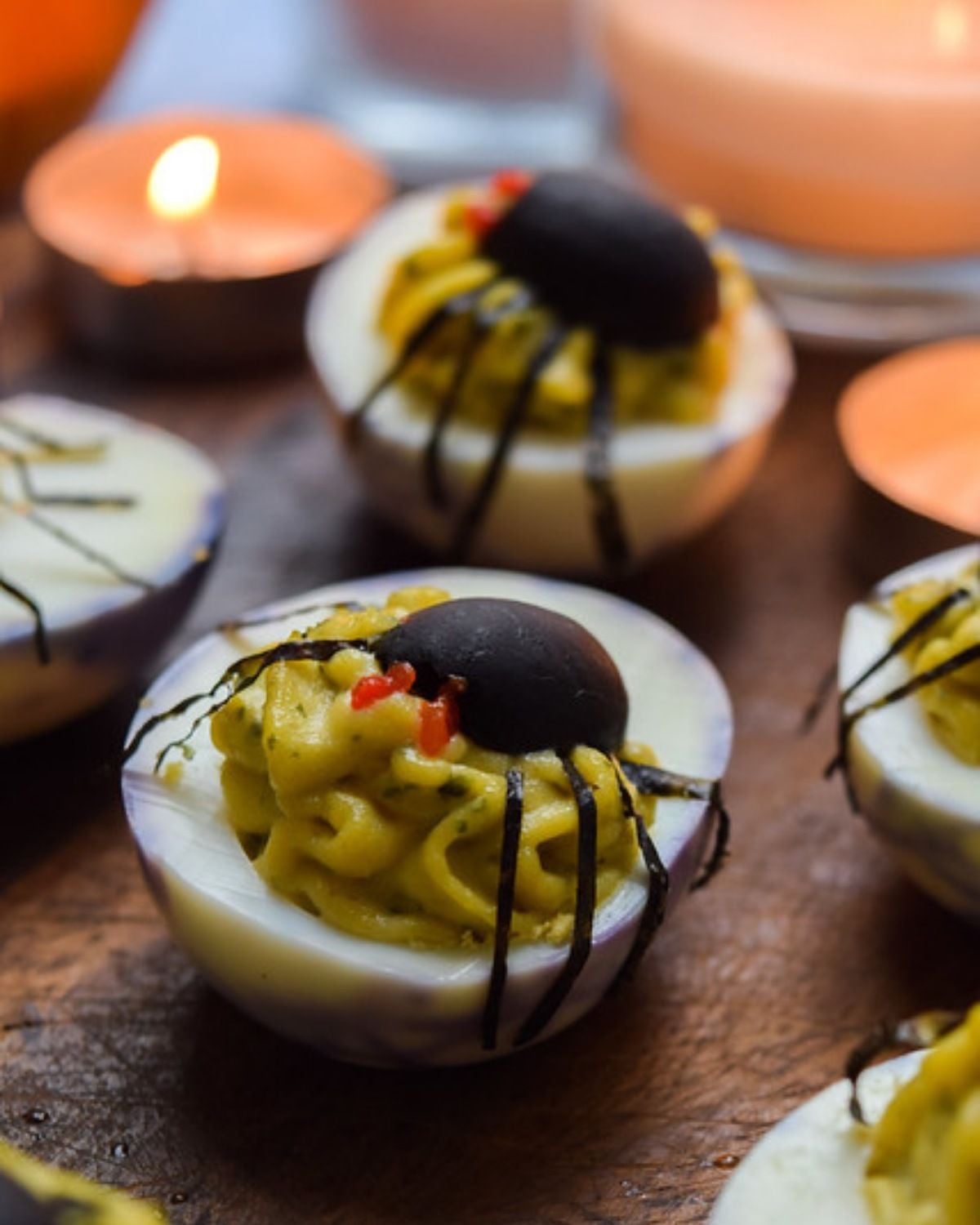 Spooky deviled eggs decorated as black olive spiders for a Halloween party food idea
