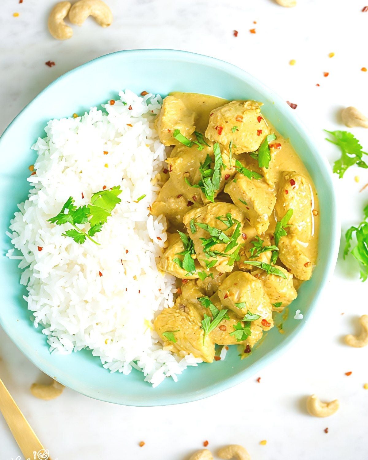 Healthy slow cooker chicken korma served over white rice with fresh cilantro and crushed red pepper.