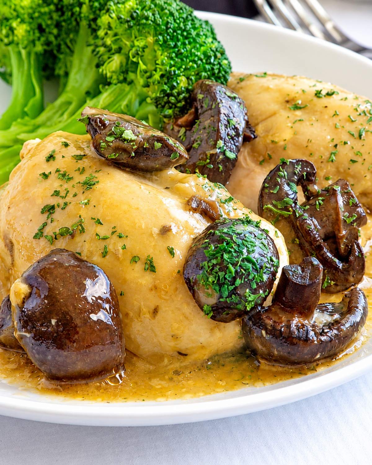 Slow-Cooker Creamy Chicken and Mushrooms served on a white plate with steamed broccoli