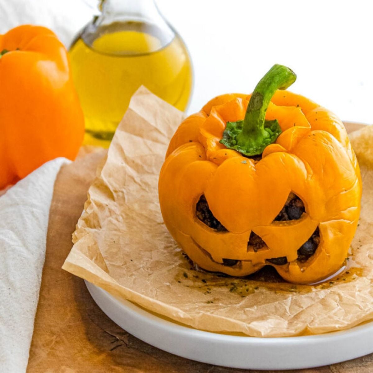 Jack-o-lantern stuffed bell pepper carved like a carved pumpkin for a Halloween party food idea.