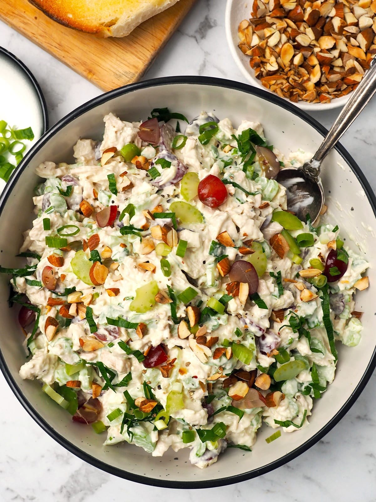 Overhead bowl of classic chicken salad with grapes, celery and almonds, with bread alongside