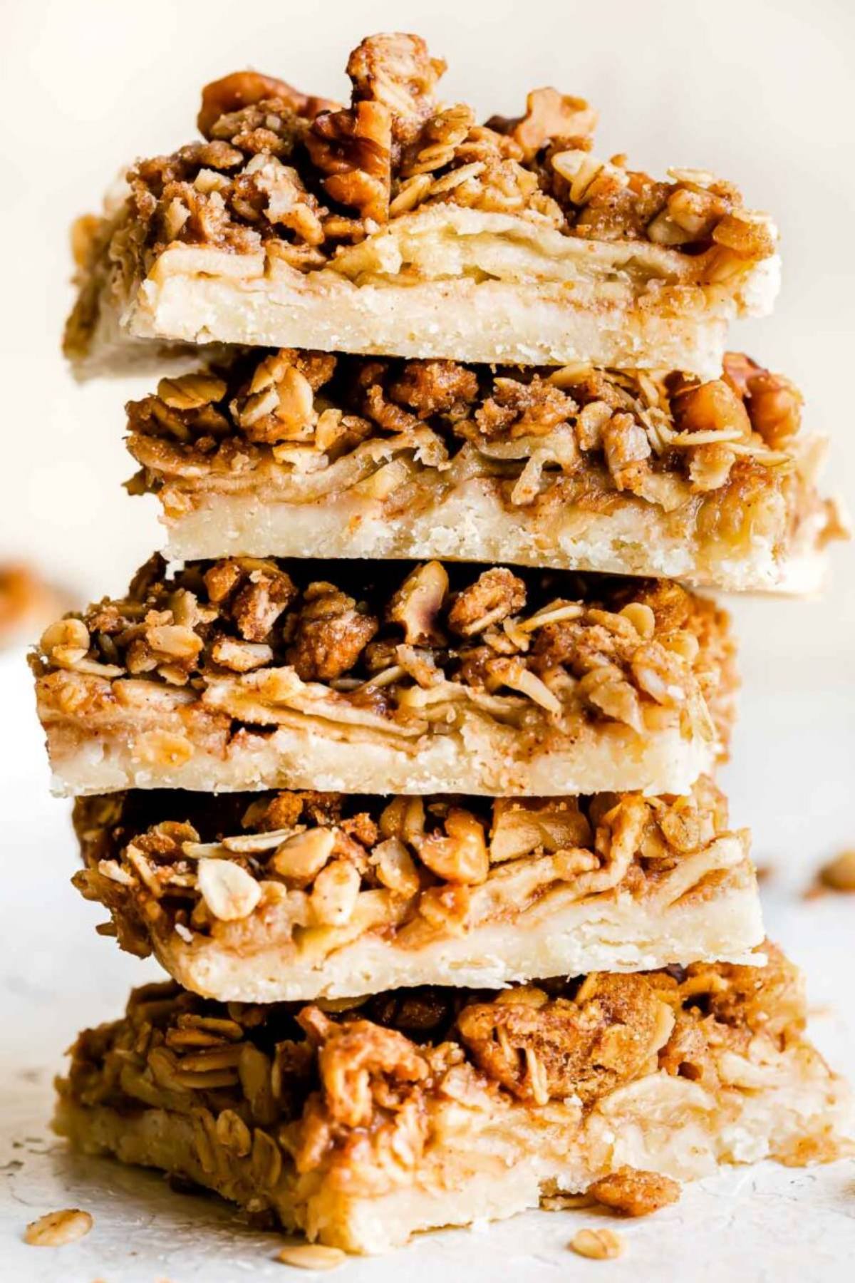 A close up view of easy fall desserts showcasing a stacked tower of apple pie bars with buttery crusts and oat crumble topping
