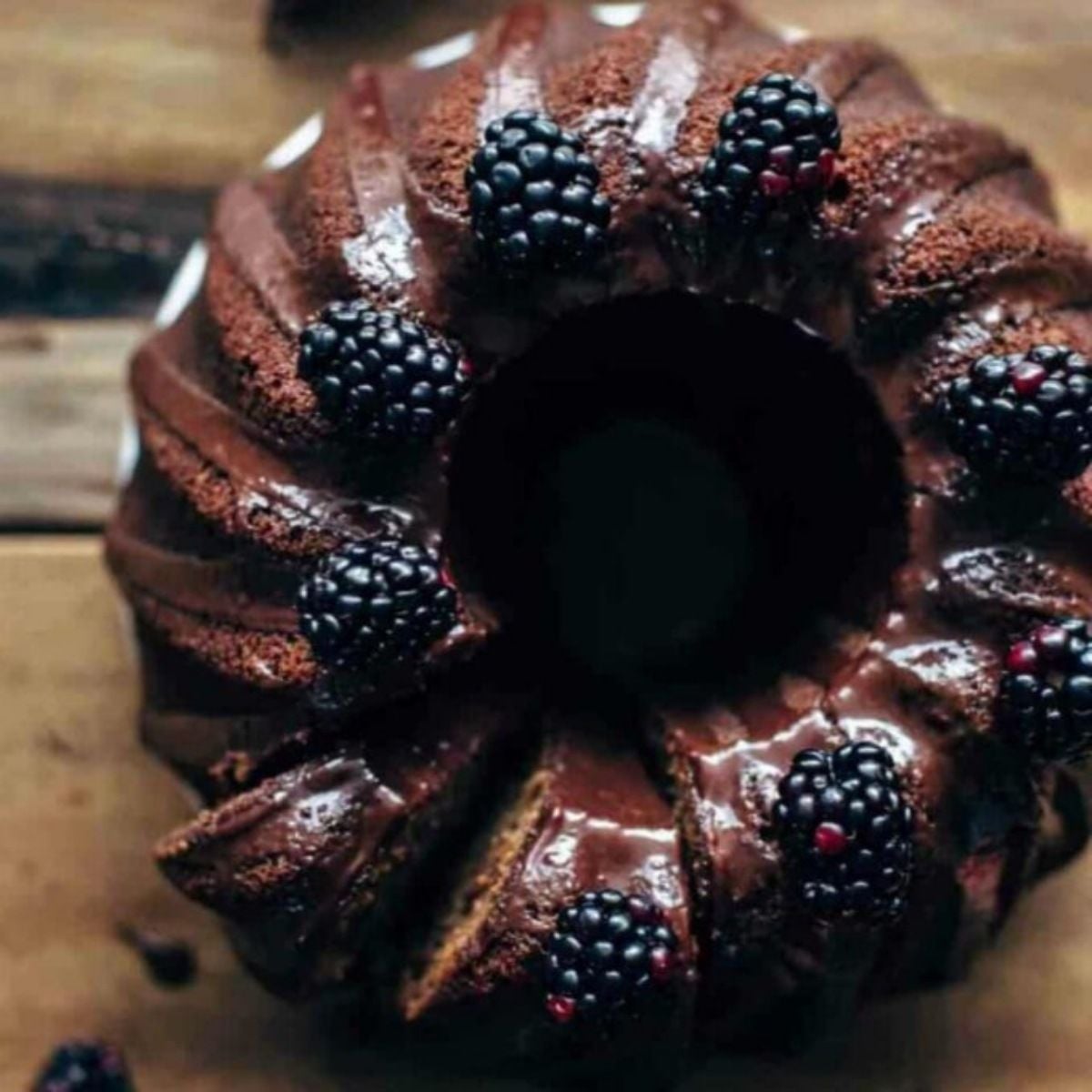 A top down view of easy fall desserts highlighting a rich chocolate glazed bundt cake garnished with fresh blackberries