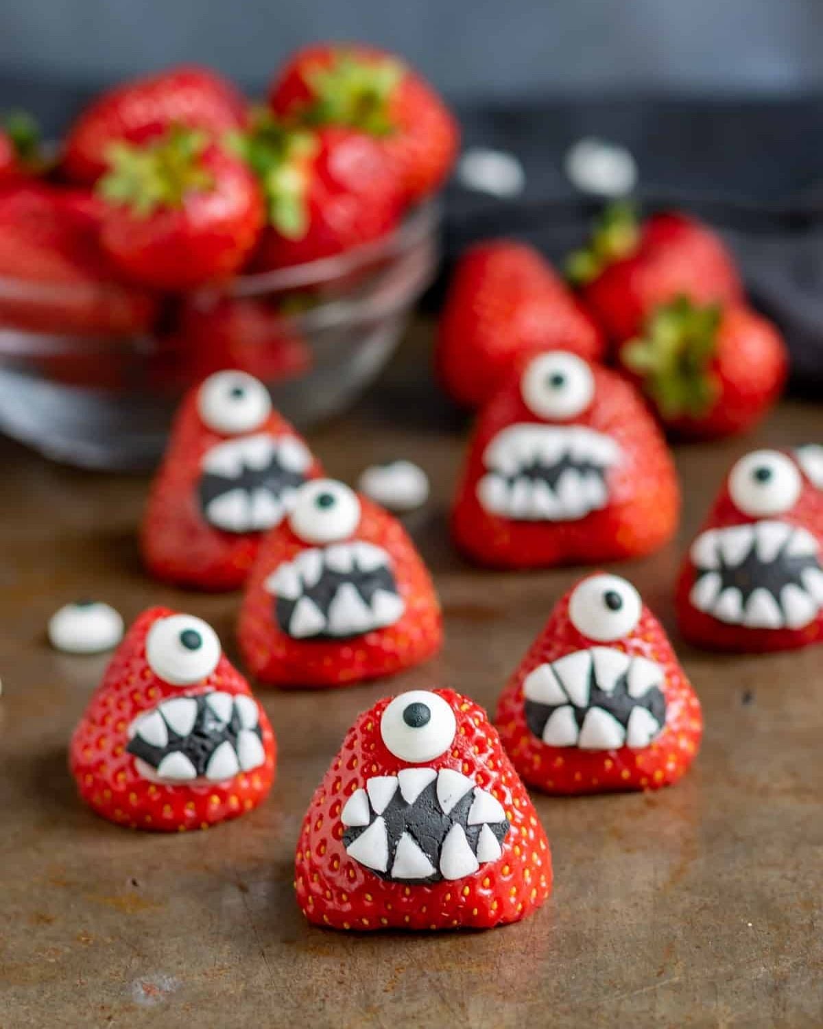 Fun strawberry monsters decorated with spooky teeth and googly eyes as a healthy Halloween treat for kids school.