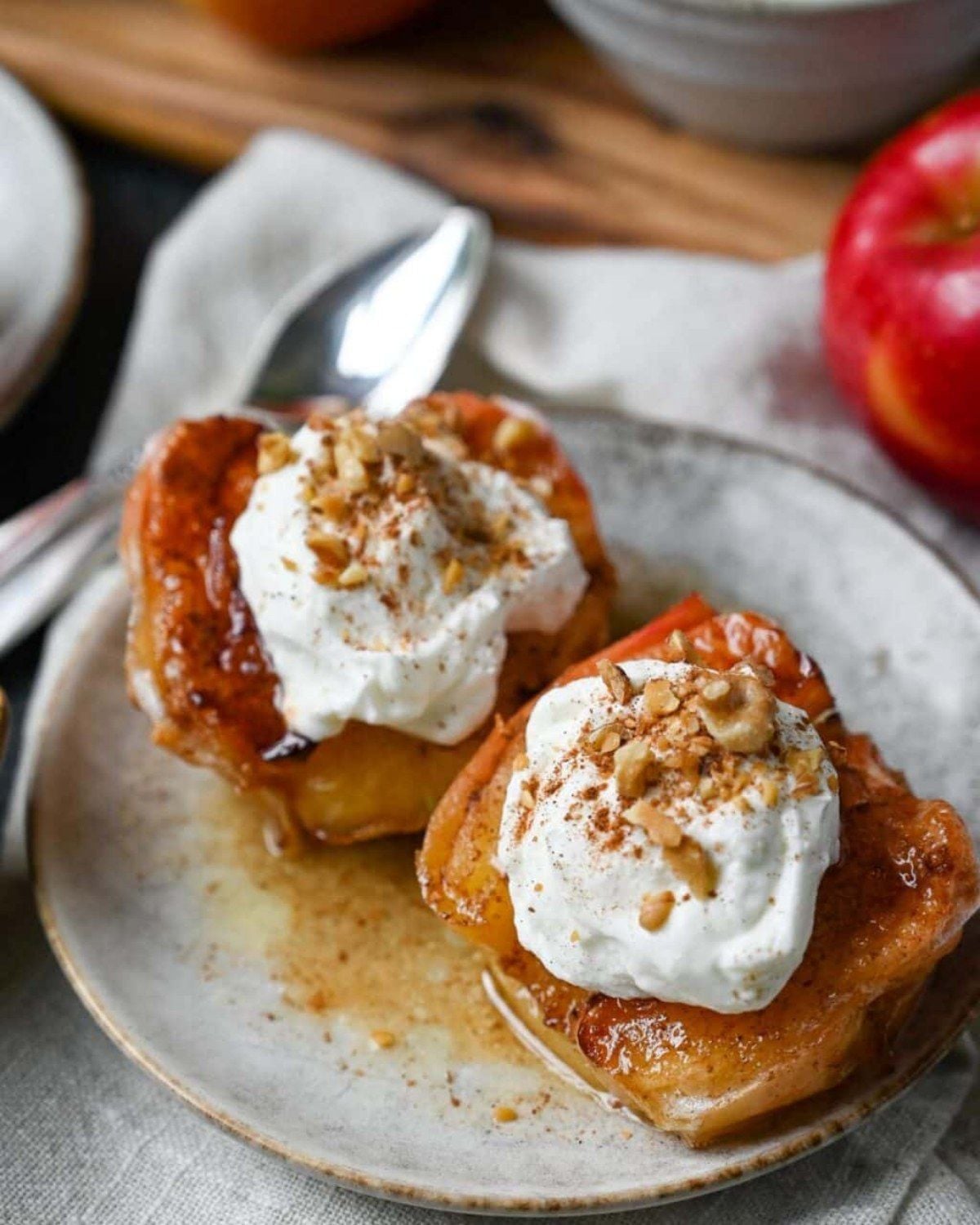Healthy fall dessert air fryer baked apples topped with whipped cream and chopped nuts on a plate