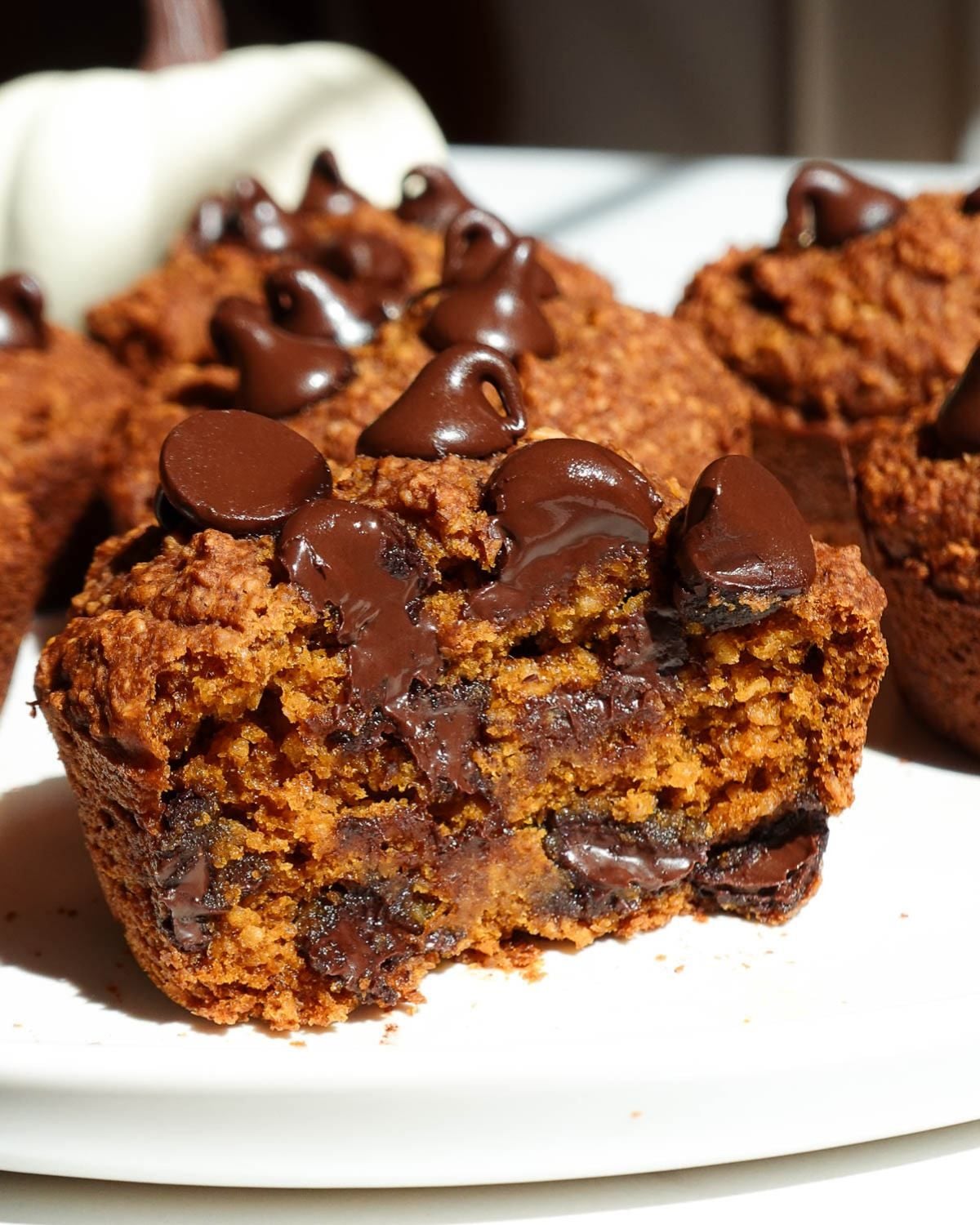 Primary Alt Text:

Healthy fall dessert chocolate chip pumpkin muffins with a bite taken out, showing melted chocolate inside