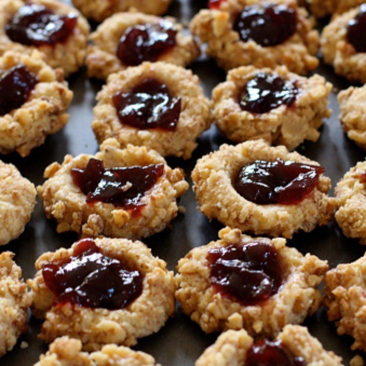 Healthy fall dessert thumbprint cookies filled with dark jam on a baking sheet