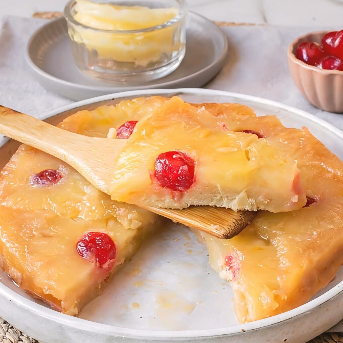 An overhead, medium shot focuses on a freshly turned, whole Pineapple Upside-Down Cake on a large, light grey, shallow stoneware platter.