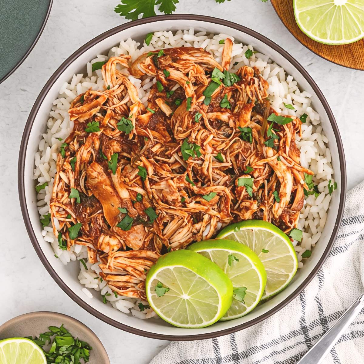 Shredded cilantro lime chicken served over a bed of white rice with fresh lime slices, making an effortless dump and go crockpot dinners chicken meal.