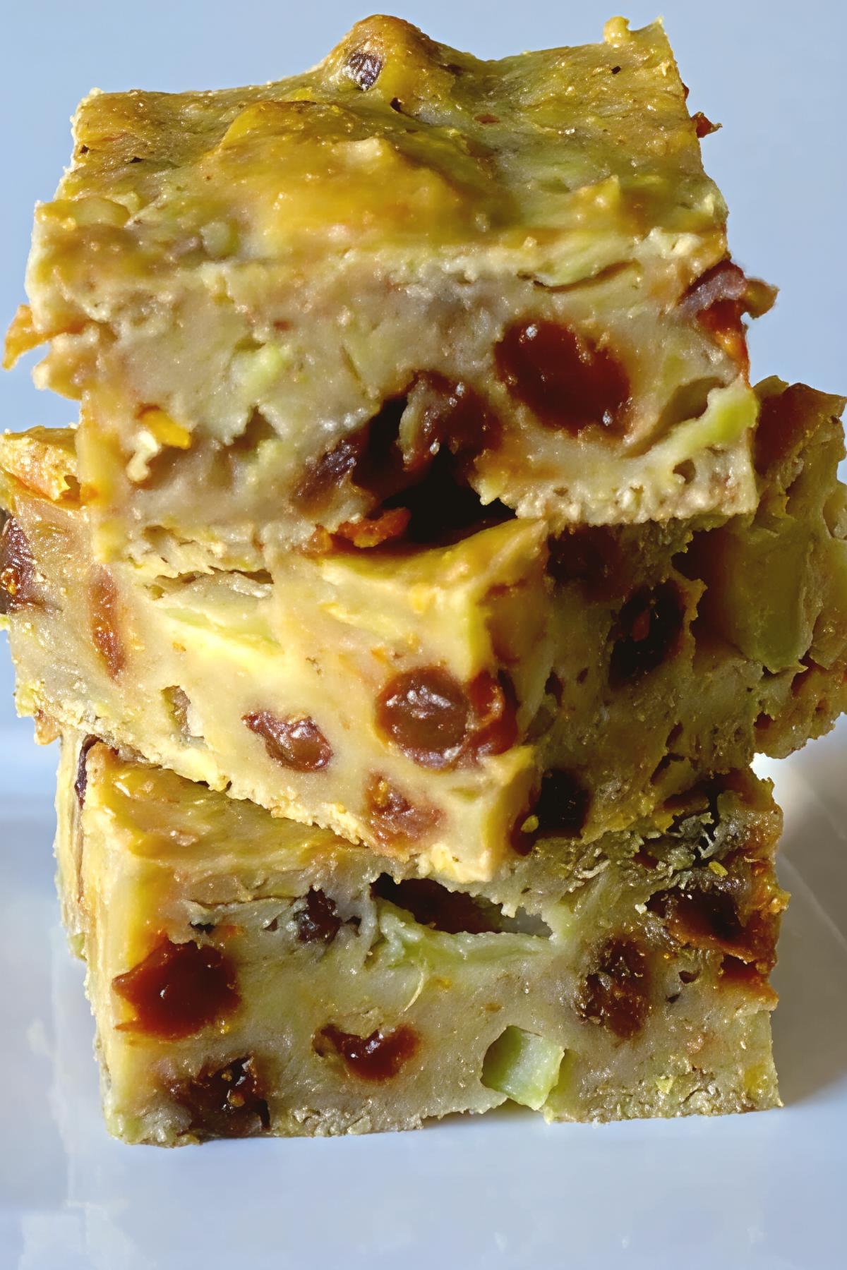 Stack of three square slices of Bustrengo, a traditional San Marino rustic fruit and nut cake studded with raisins and apples.