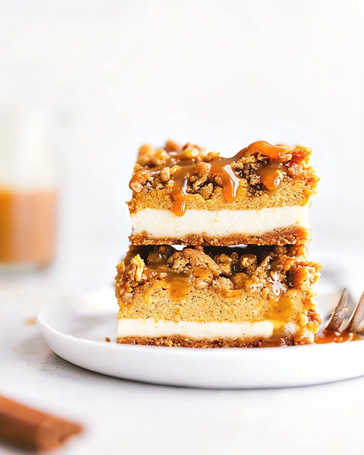 Warm caramel apple crisp layered with sliced cinnamon apples and a crunchy oat streusel topping, crowned with a scoop of vanilla ice cream on a white plate
