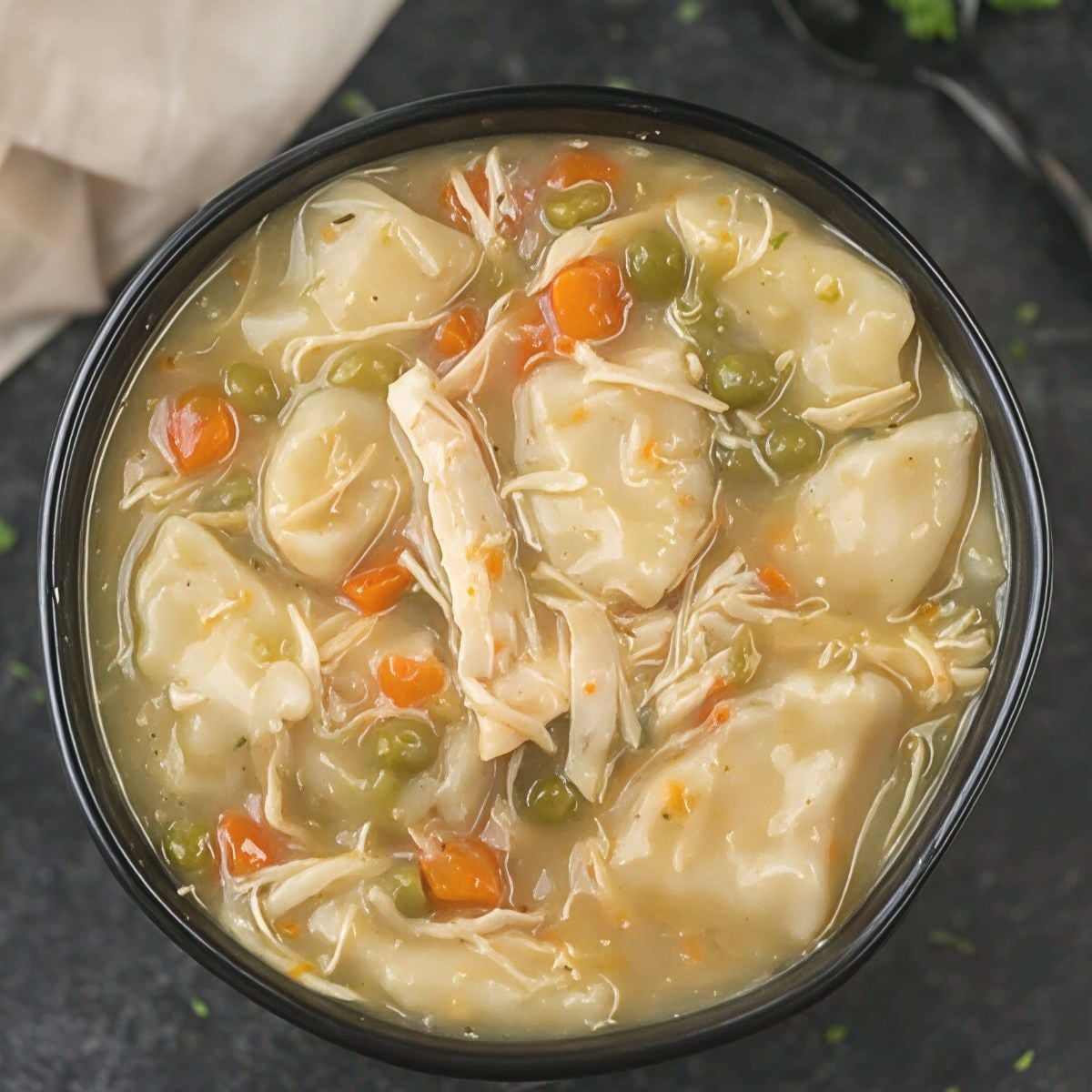 A warm bowl of comforting chicken and dumplings filled with tender chicken, vegetables, and fluffy dough, making a cozy dump and go crockpot dinner (Lazy Dinner).
