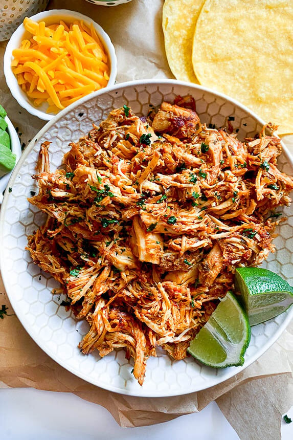 Shredded cilantro lime chicken served over a bed of white rice with fresh lime slices, making an effortless dump and go crockpot dinners chicken meal.