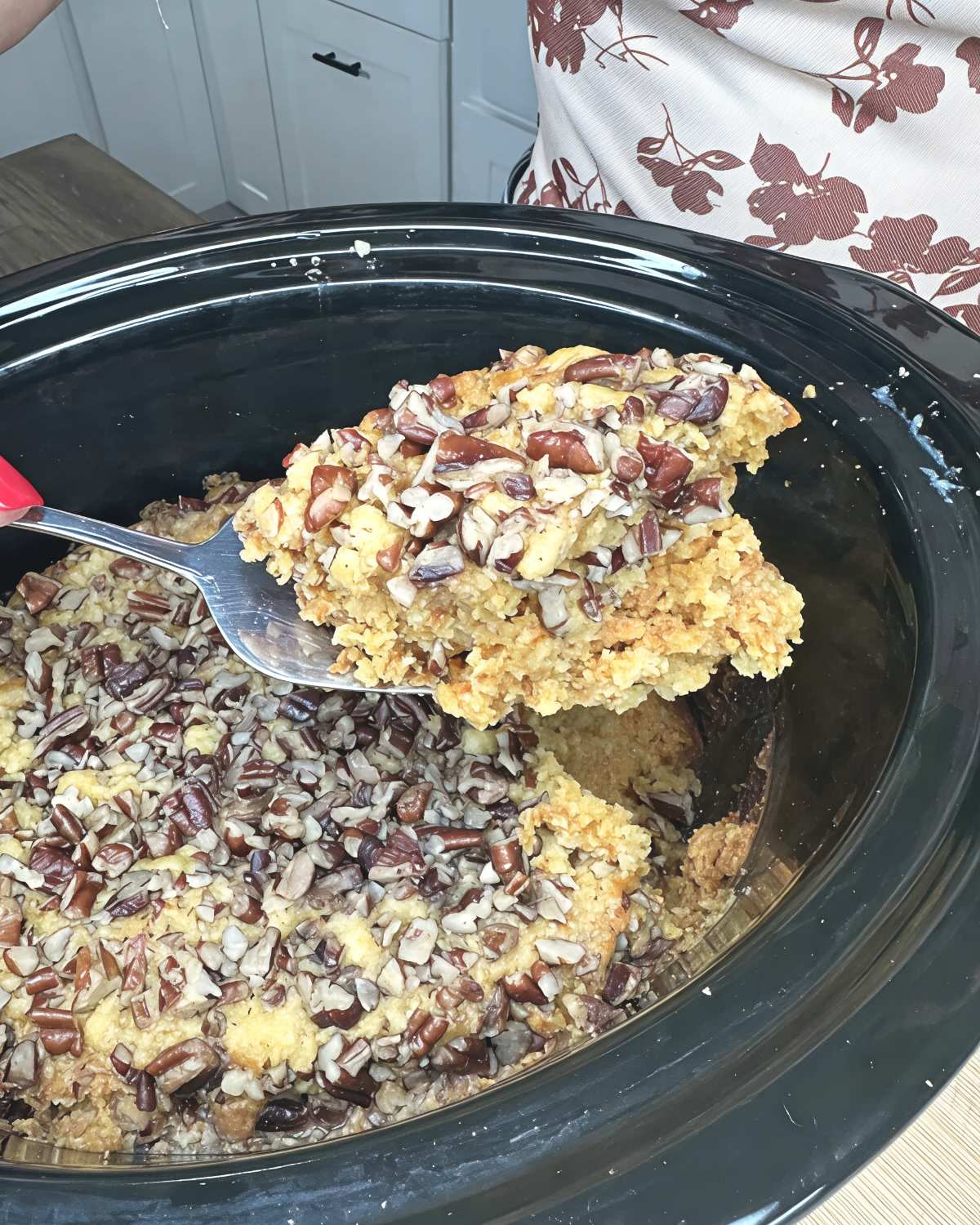 Spatula scooping warm crockpot pumpkin crunch cake topped with crunchy chopped pecans directly from a slow cooker, perfect for crockpot thanksgiving recipes.