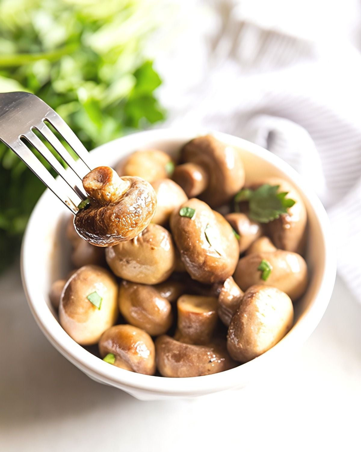 Tender whole button mushrooms slow-cooked in a buttery ranch seasoning and served in a white bowl, perfect for crockpot thanksgiving recipes.