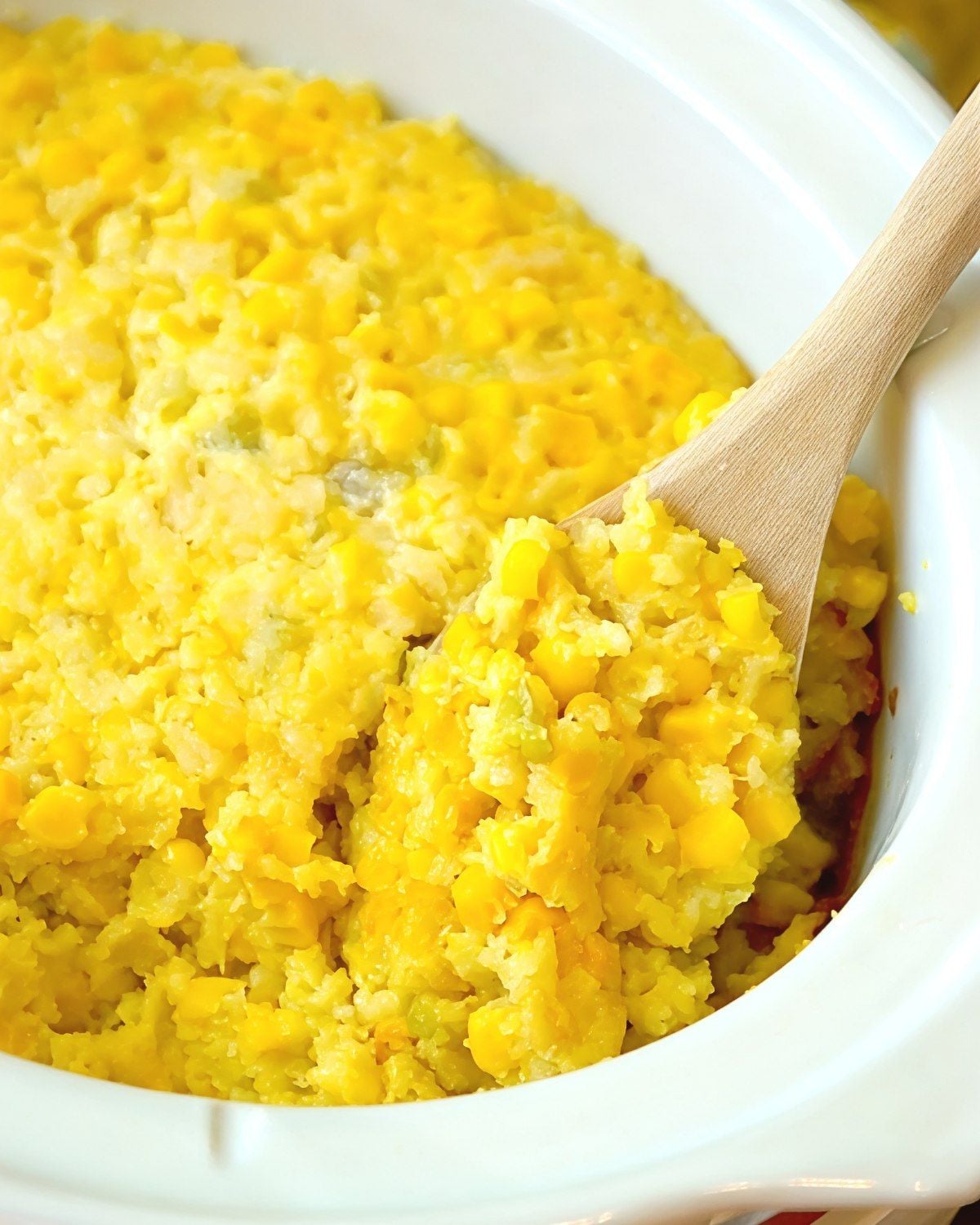 Creamy crockpot corn casserole being scooped with a wooden spoon directly from the slow cooker, perfect for crockpot thanksgiving recipes.