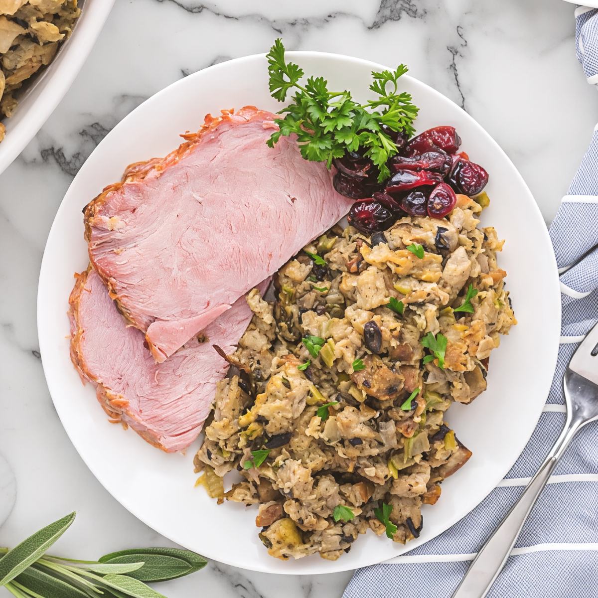 Moist crockpot stuffing thanksgiving recipe served on a plate with sliced ham and cranberries.