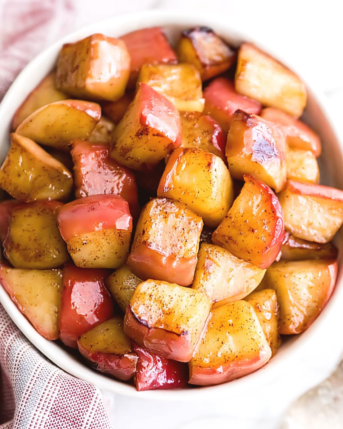 Tender diced red apples tossed in ground cinnamon and glazed to perfection served in a white bowl for an easy Thanksgiving dessert