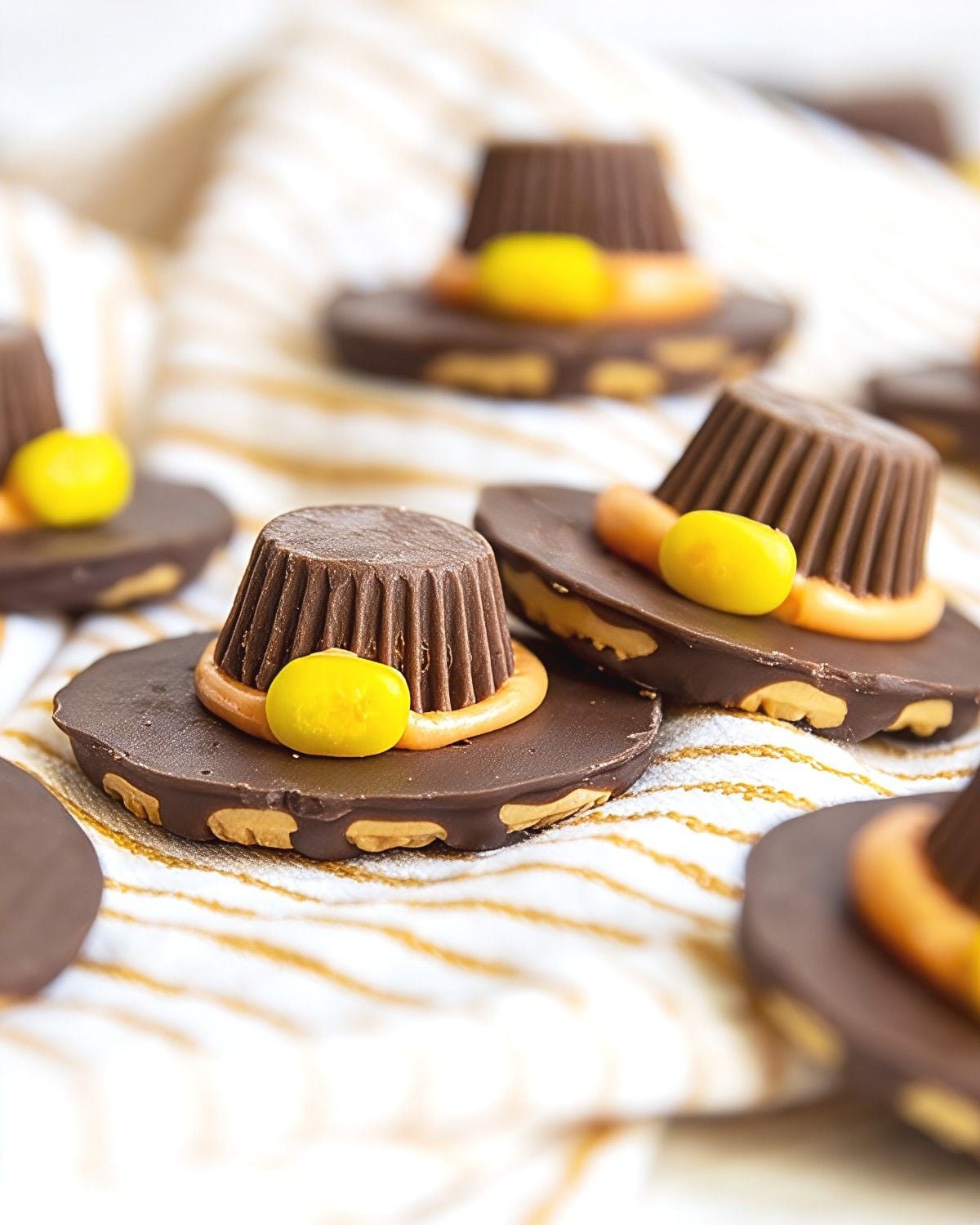 Festive pilgrim hat cookies made with chocolate-covered cookies, miniature peanut butter cups, and yellow candy buckles for easy Thanksgiving desserts.