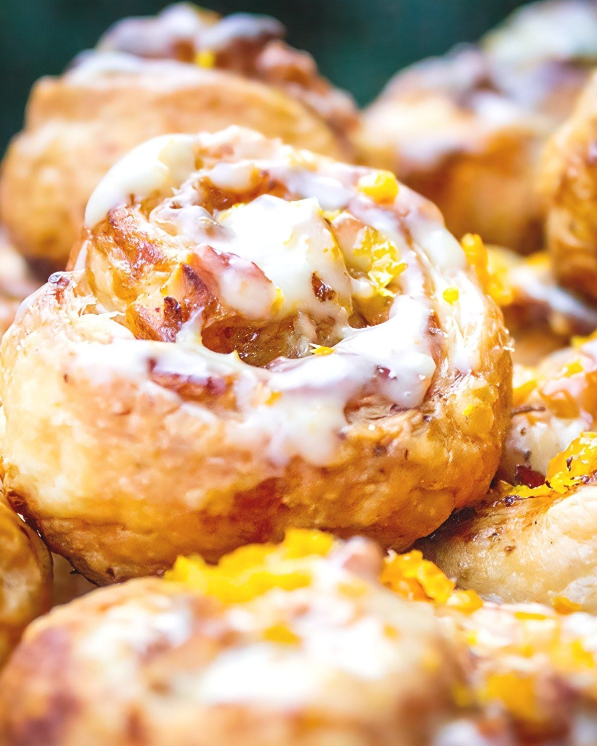Golden-brown mini puff pastry cinnamon rolls drizzled with white icing and sprinkled with orange zest for an easy Thanksgiving dessert.