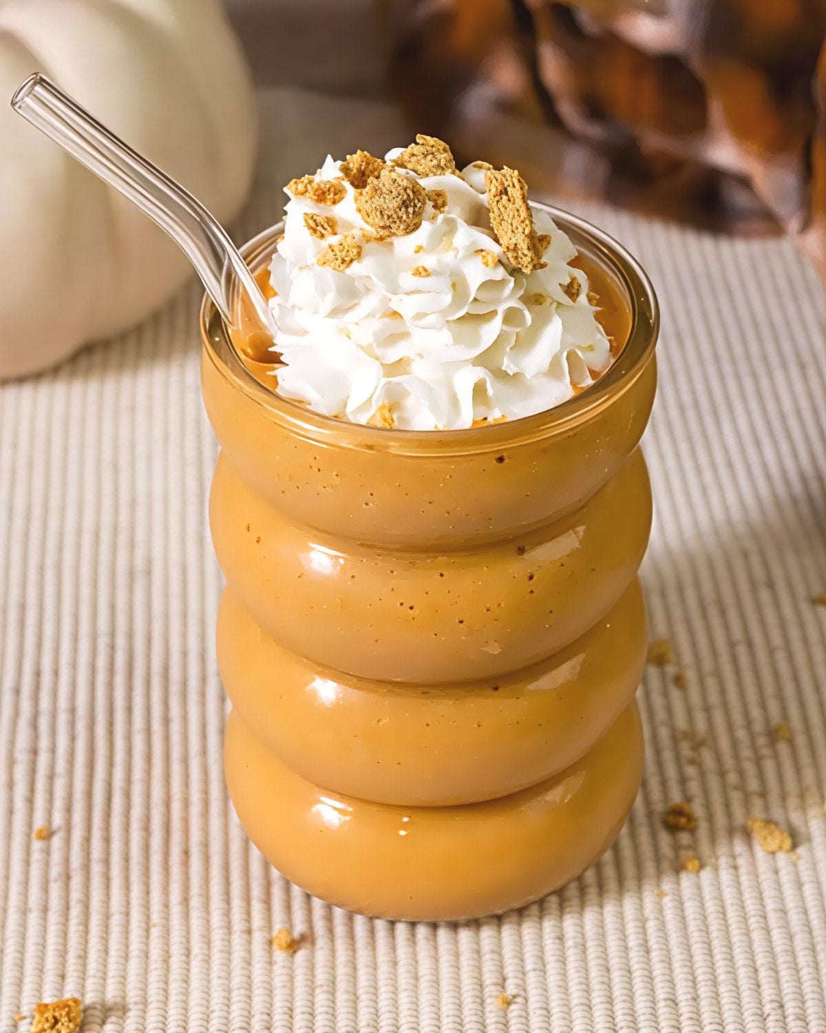 Creamy pumpkin pie milkshake topped with whipped cream and graham cracker crumbs served in a ridged glass with a straw for an easy Thanksgiving dessert.