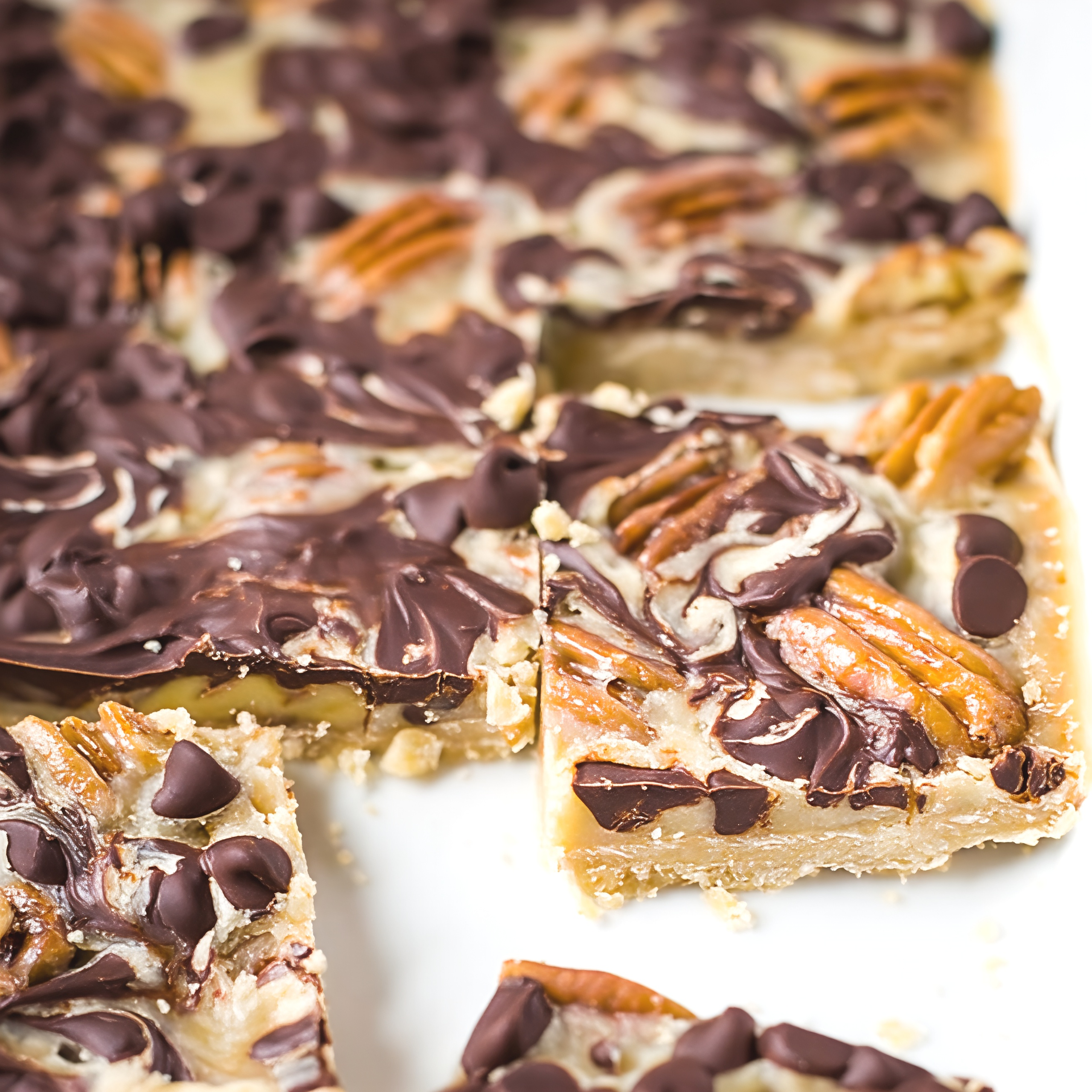 Decadent turtle cookie bars layered with shortbread, pecans, and melted chocolate chips sliced for an easy Thanksgiving dessert.