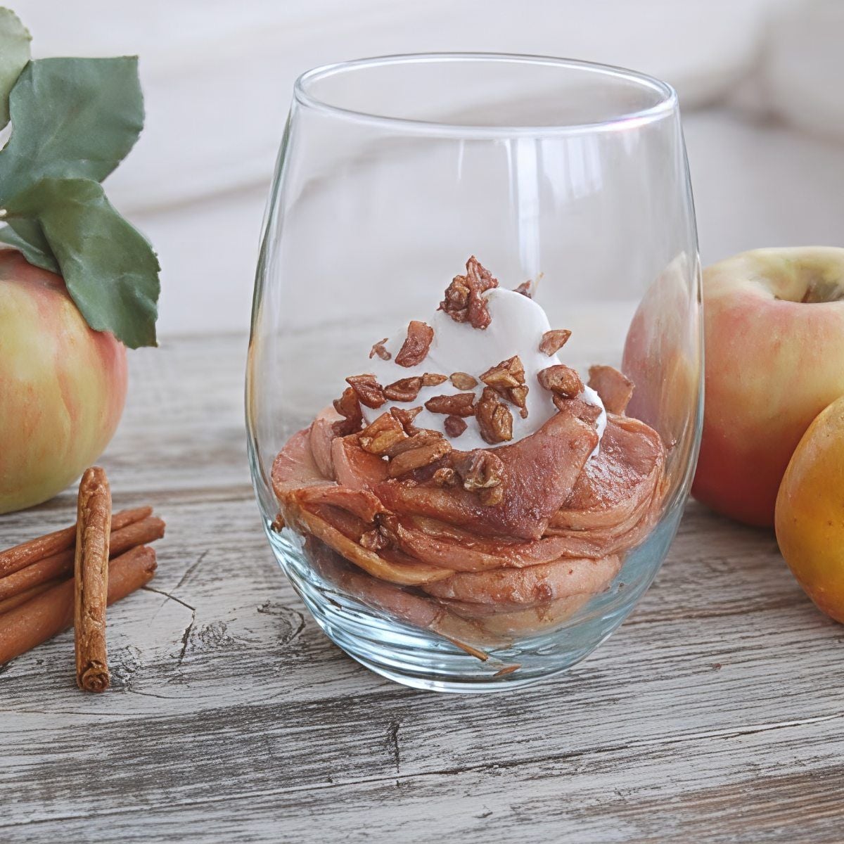 A glass serving of crustless vegan apple pie layered with spiced apples, whipped cream, and chopped pecans, ideal for gluten-free Thanksgiving desserts.